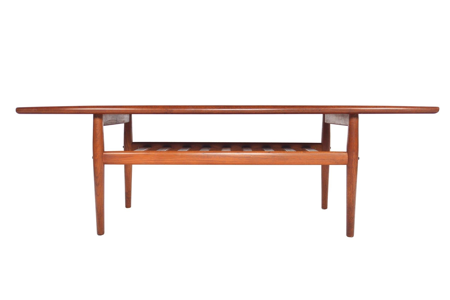 This elegant Danish modern midcentury surfboard coffee table was designed by Grete Jalk for Glostrup Møbelfabrik in the 1960s. Beautiful book match veneer is flanked by raised lips. A lower rack offers storage. In excellent original condition.
 
  