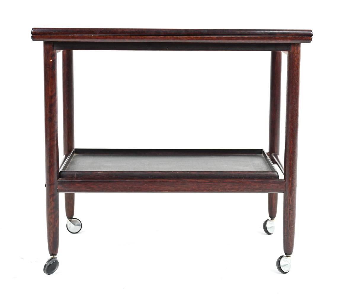 A fantastic Danish mid-century expandable flip top bar or tea cart, on casters. This fabulous trolley features a removable lower tier tray and a flip top that expands to 35