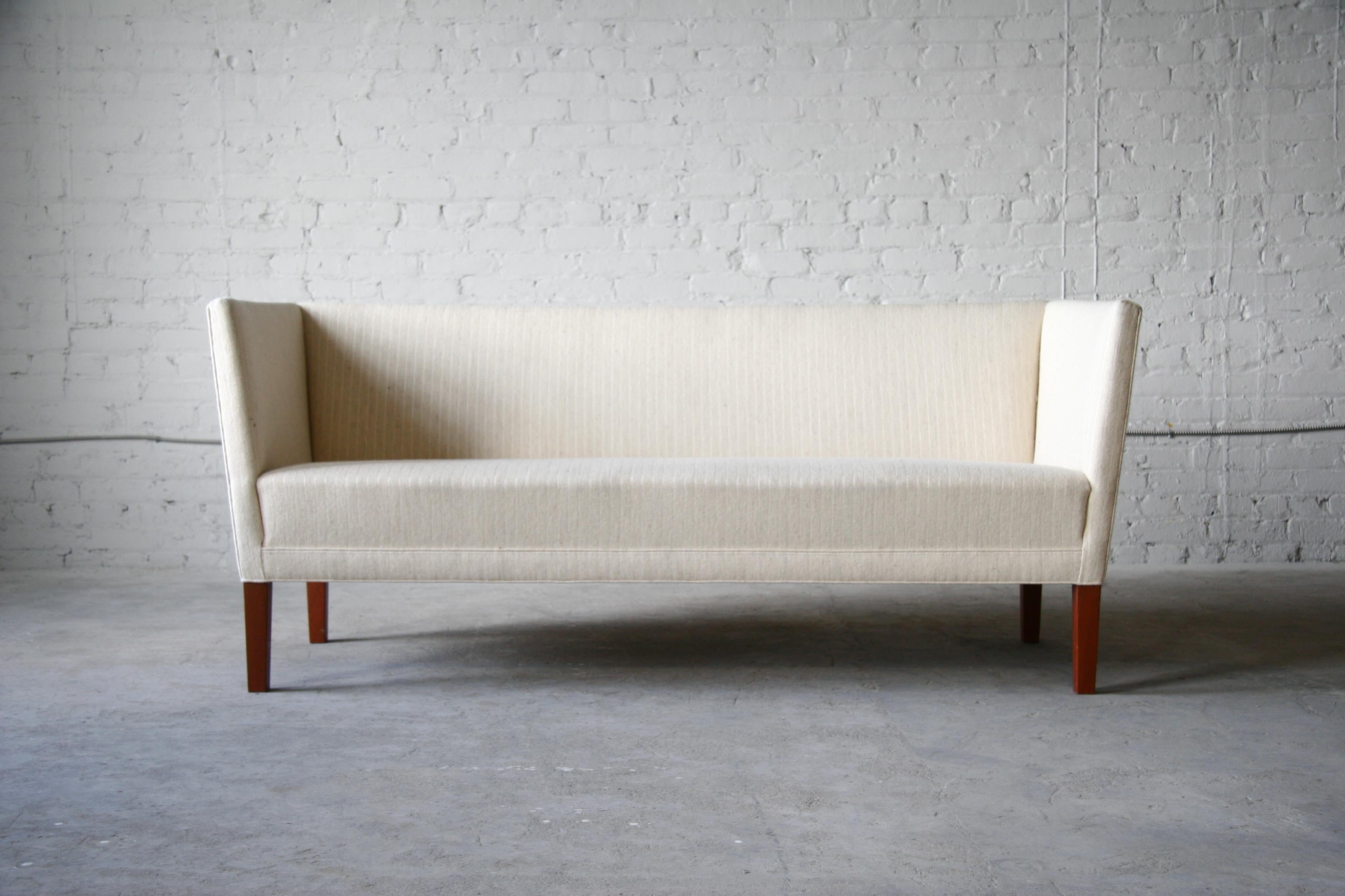 A mahogany sofa by Grete Jalk for Johannes Hansen. As far as we know, this is the only design Jalk created for Johannes Hansen. It is a linear and minimalist box style sofa that envelopes one who sits in it. 

The sofa sits atop solid mahogany