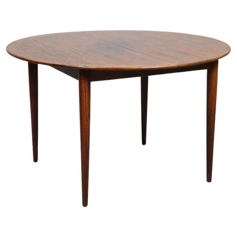 Elegante table en bois de rose massif de la designer Grete Jalk. Produit dans les années 1960 par l'ébéniste Poul Jeppessens. Nous disposons de 4 chaises avec dossier et assise en cuir noir, assorties à la table. 8 autres chaises avec assise en cuir