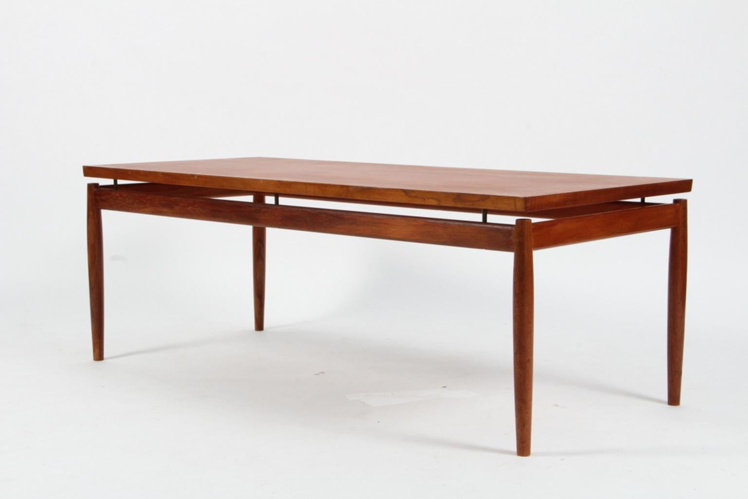 Grete Jalk sofa table with floating tabletop, tabletop held by brass pieces. Top of veenered teak, base of solid teak.

Model 622 / 54, made by France & Son in the 1960s.