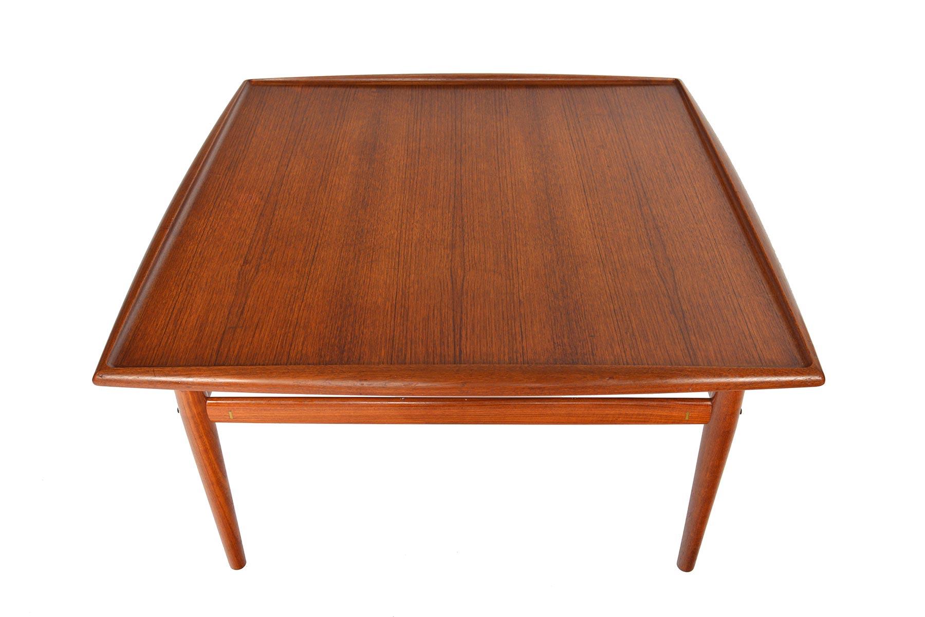 A staple of Scandinavian design, this square teak coffee table was designed by Grete Jalk for Glostrup Møbelfabrik in the 1960s. A large teak table surface features a curved lip which runs the banding. In excellent original condition.

  