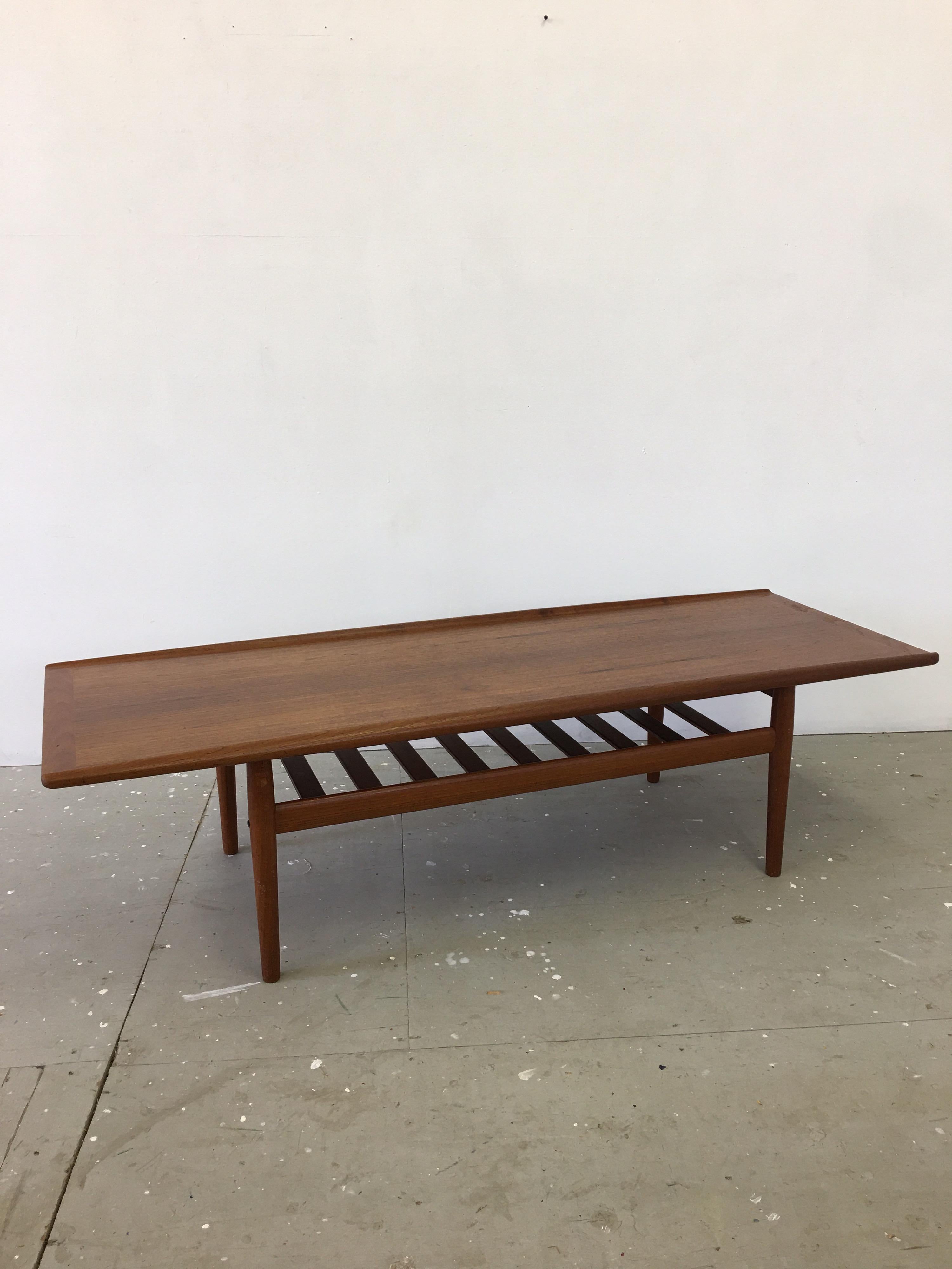Grete Jalk Teak Coffee Table with stretcher lower shelf, perfect storage for magazines and books!  Table has a Thick Round Edge design to the two long sides.   Solid teak legs and stretchers! Small brass details to inner legs.