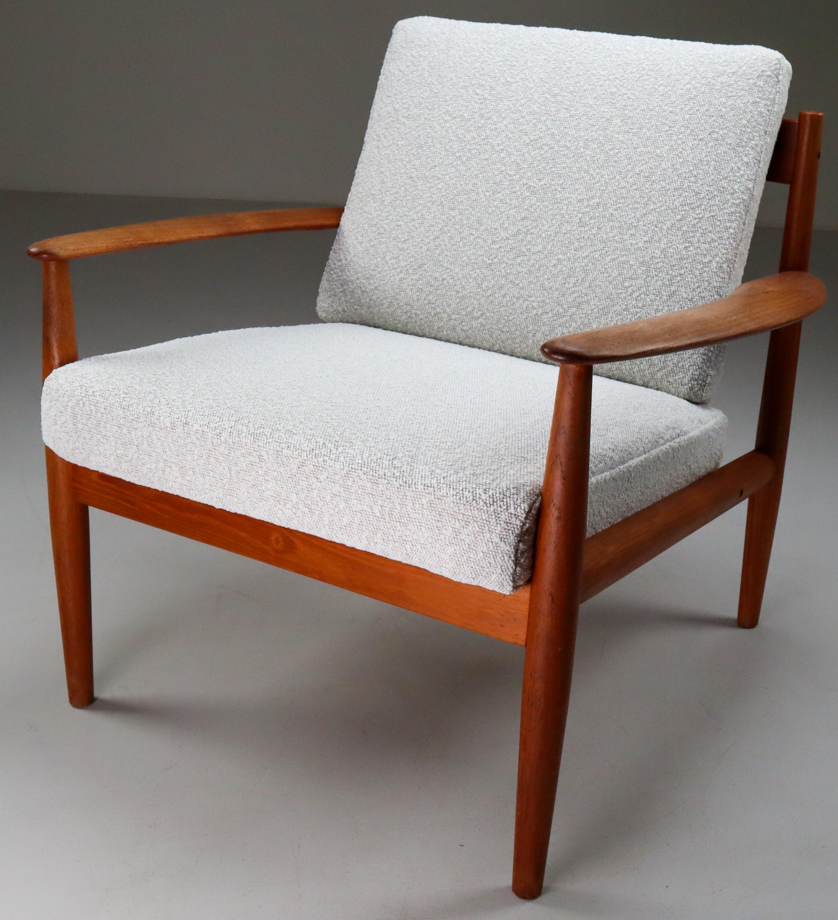 Elegant lounge chair designed by one of the few female midcentury furniture designers, Grete Jalk, in Denmark for France & Søn, circa 1960s. Constructed of teak wood and reupholstery bouclé cushions, two curved slats adorn the open back of this