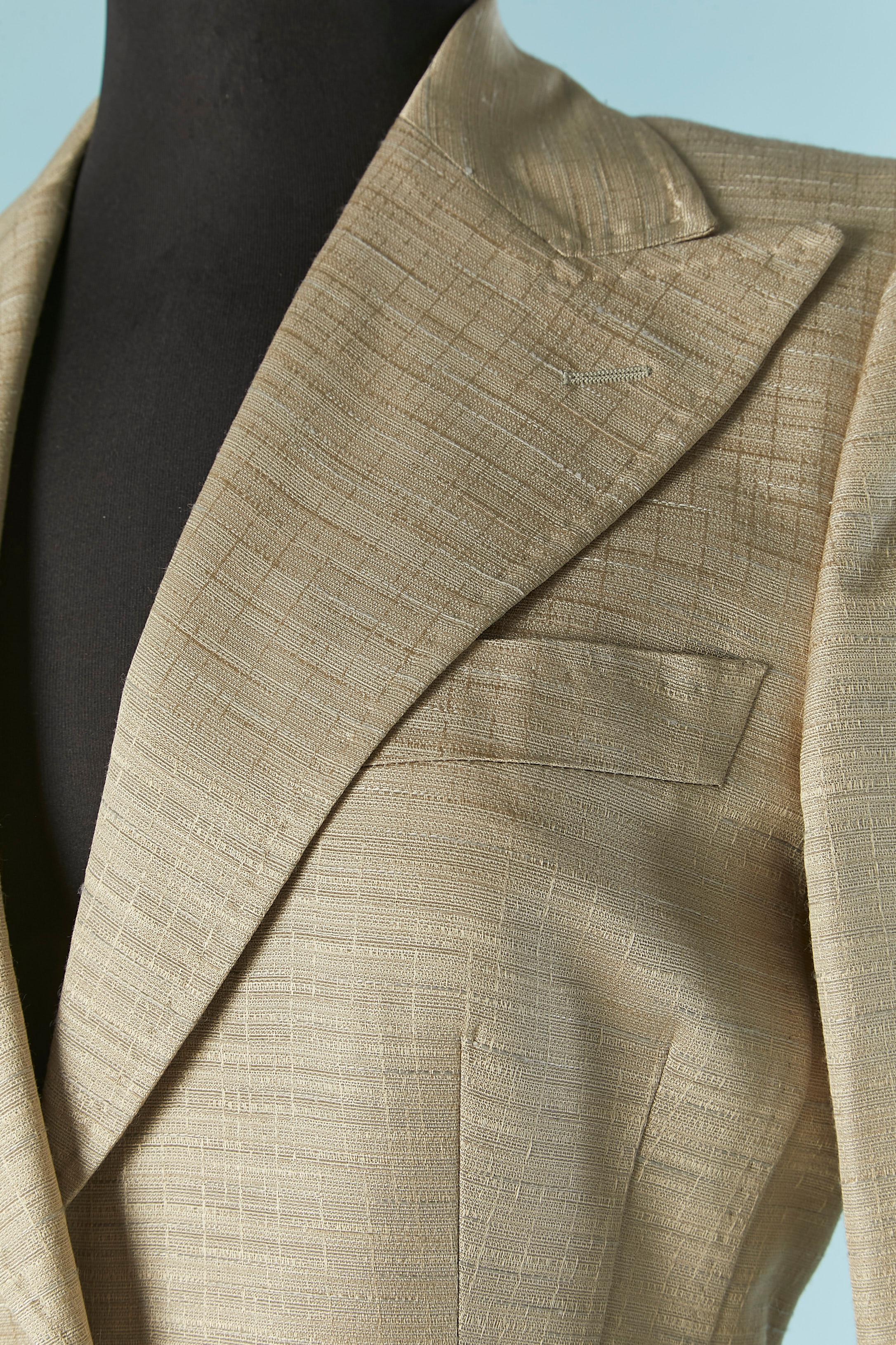 Traje pantalón gris y dorado pálido. composición del tejido principal: 59% rayón, 27% seda, 14% algodón. Composición del forro: rayón y cupro.
Hombrera. Botón de marca y cierre de ojal en la parte delantera central . Botón en los puños ( sin ojal) 3