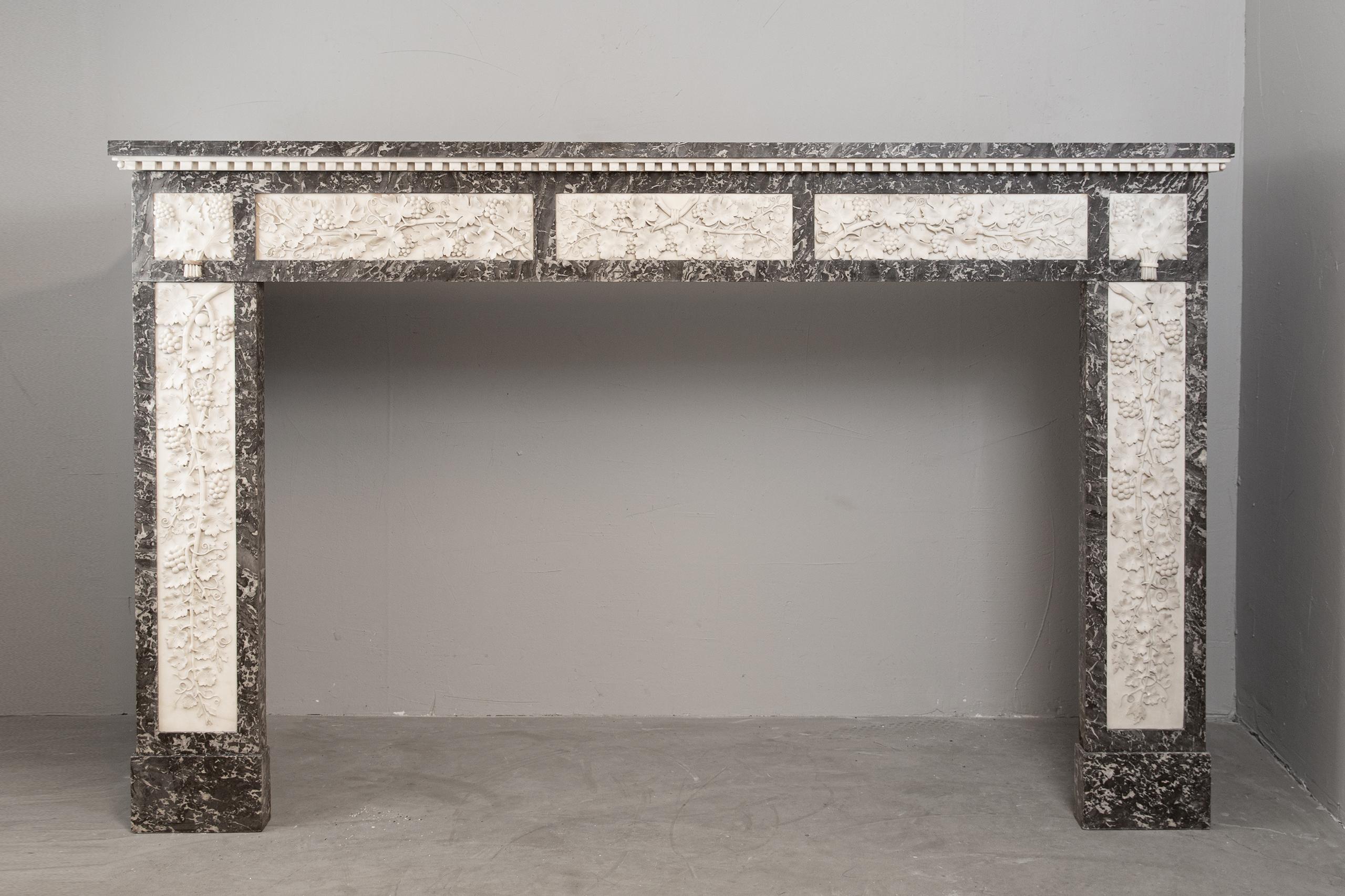 This Antique Louis XVI period fireplace in carrara and gray marble decorated with grapevines and grapes.
This fireplace is in very good condition. With its richness and decoration with hewn grapes and grape branches is an absolute centerpiece in