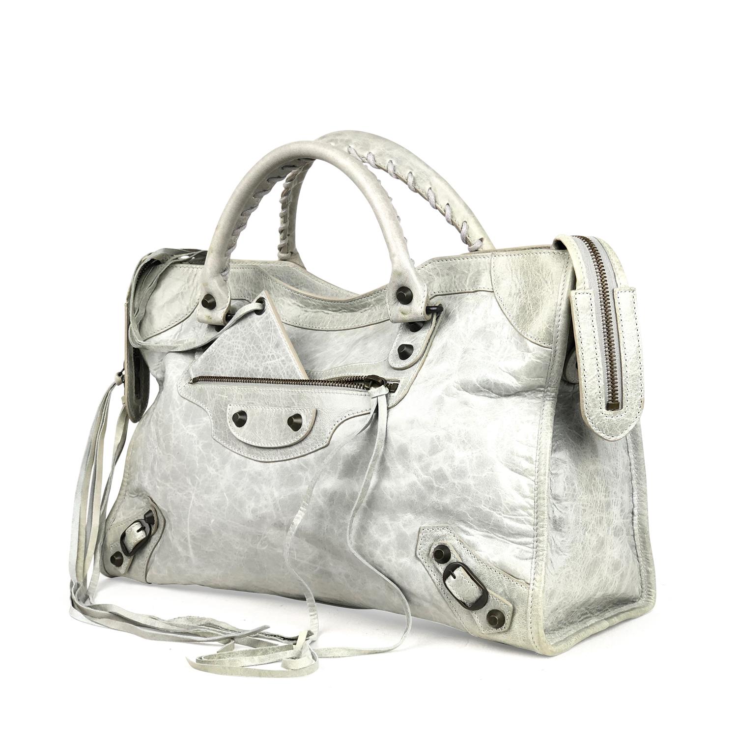 Grey Arena leather Balenciaga Classic City bag with

- Brass hardware
- Dual rolled top handles featuring whipstitch trim
- Detachable flat shoulder strap
- Single zip pocket and stud embellishments featuring buckle adornments at front
- Black woven