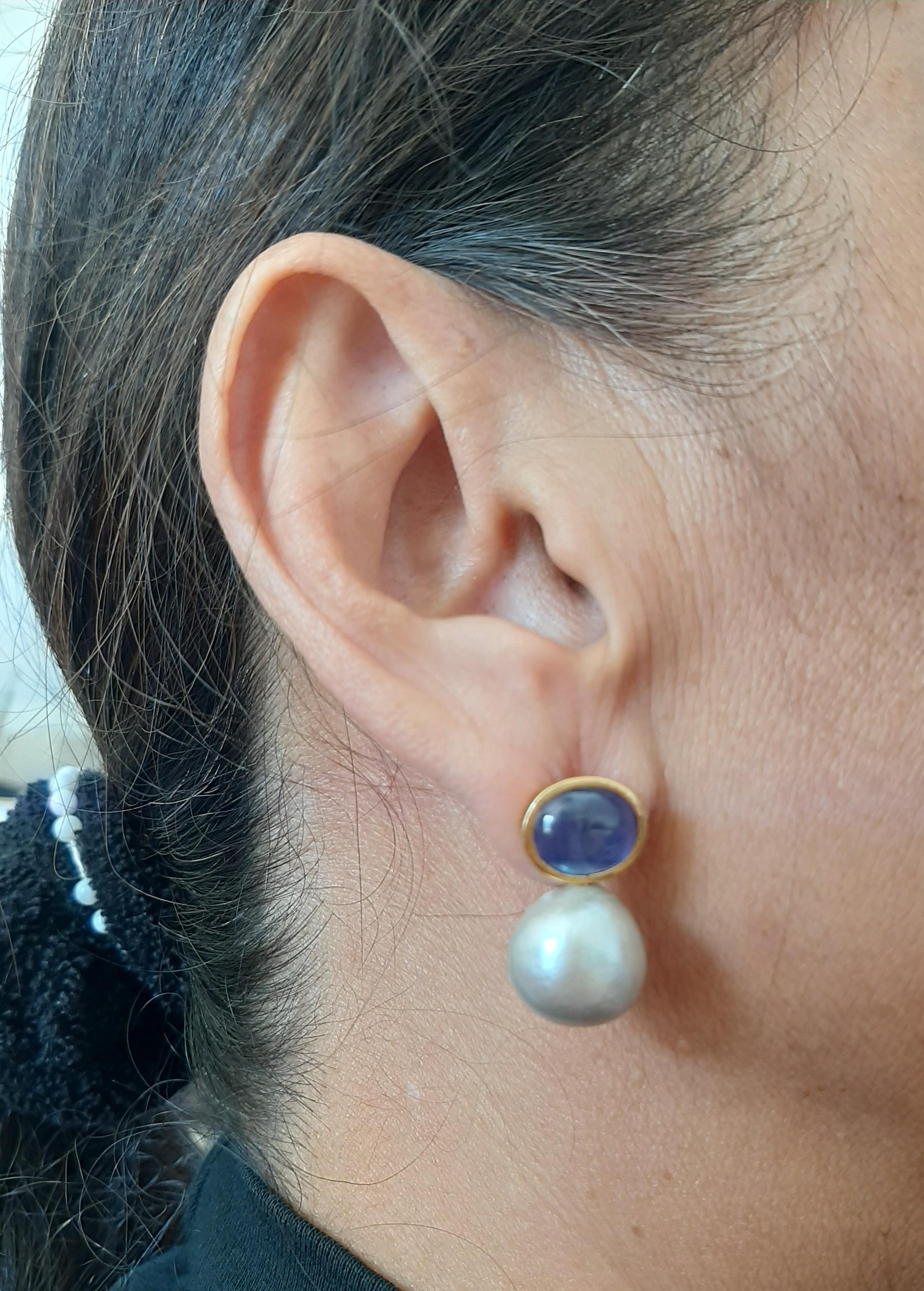 Ces boucles d'oreilles simples et chics faites à la main ont une paire de saphirs bleus de forme ovale mesurant 9 x 11 mm et pesant 8,7 carats sertis dans un chaton en or jaune 14 carats sur le dessus et dans les parties inférieures 2 perles