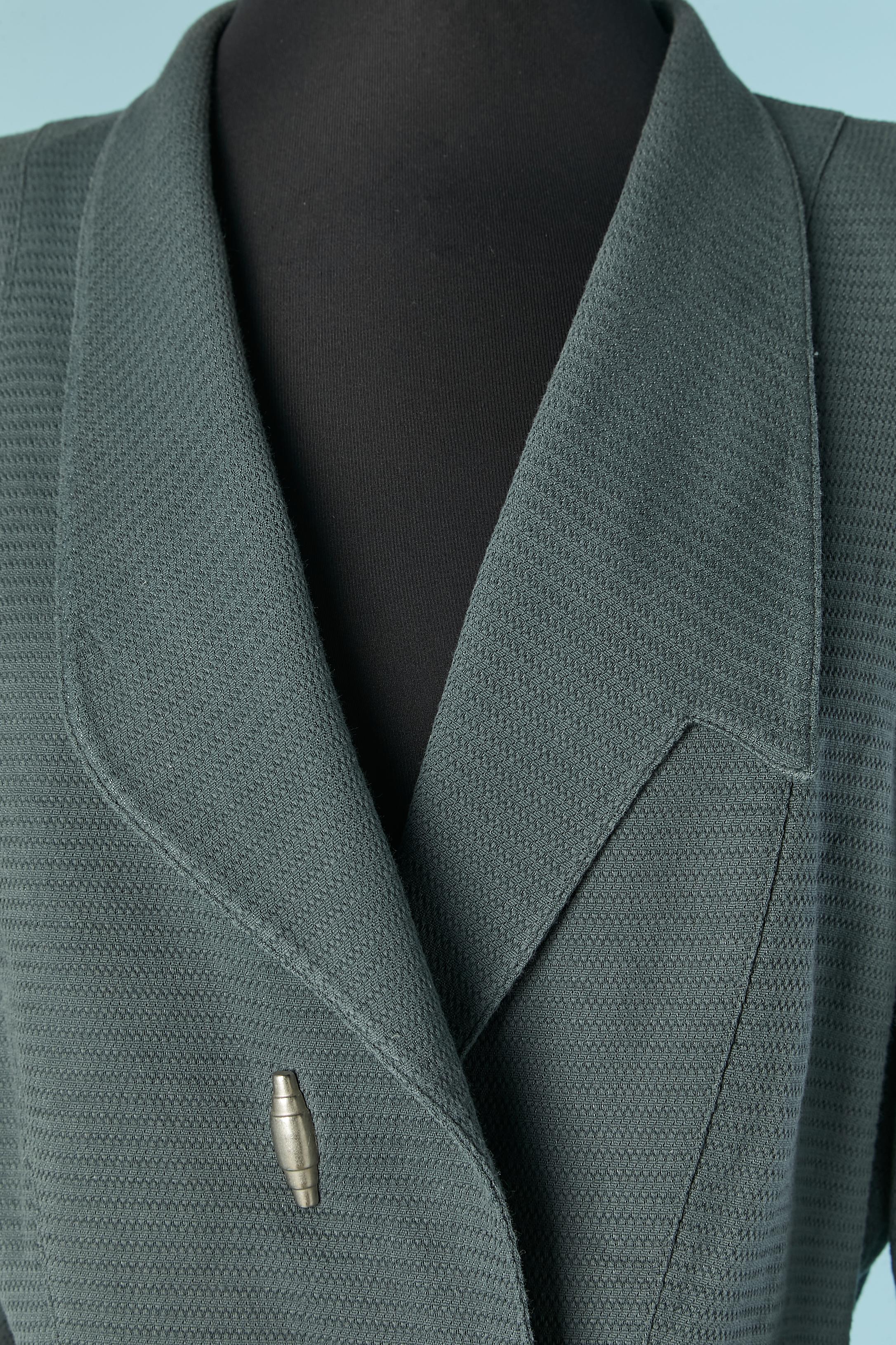 Chaqueta asimétrica de doble botonadura gris-azul. Composición del tejido: 60% algodón, 40% rayón. Composición del forro: 65% acetato, 35% rayón. 
Cierre a presión en la parte delantera ( el de arriba es decorativo, no hay parte trasera del cierre a