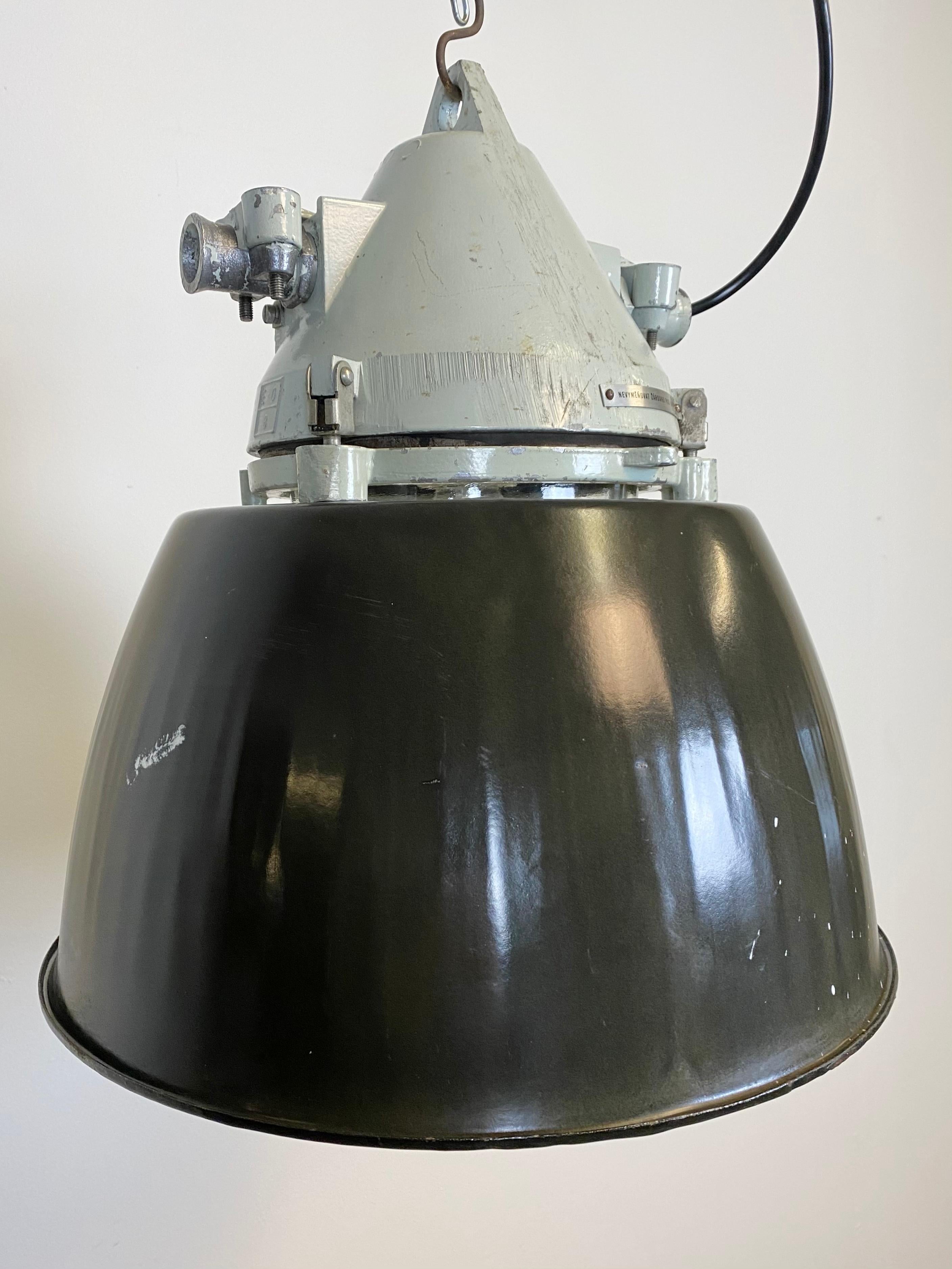 Grey industrial lamp with massive protective glass bulb made by Elektrosvit in former Czechoslovakia during the 1970s.It features a cast aluminium body, a clear glass and a black enameled shade with white interior. Porcelain socket requires E27