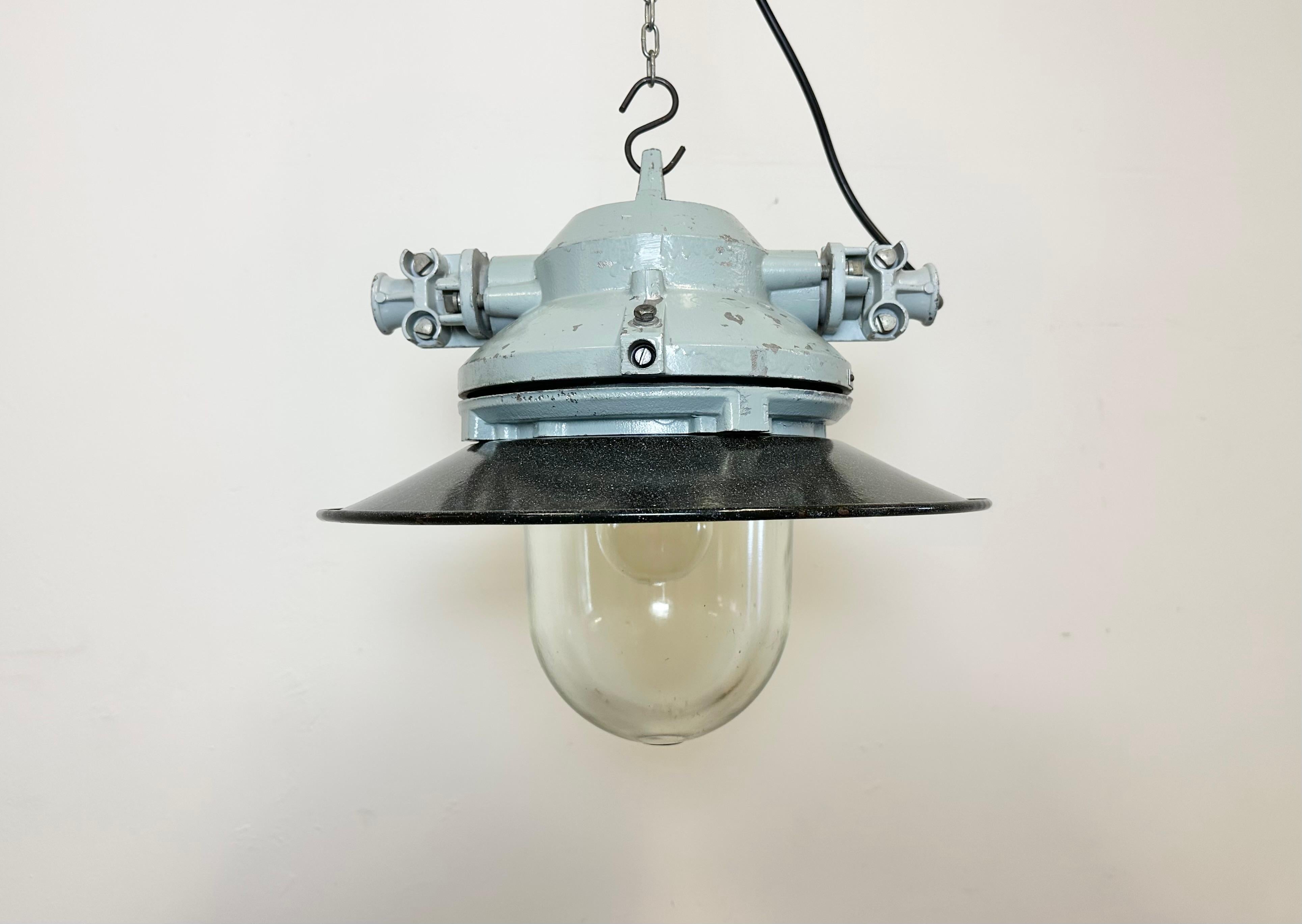 Graue Industrielampe mit massivem Schutzglaskolben, hergestellt von Elektrosvit in der ehemaligen Tschechoslowakei in den 1970er Jahren, mit einem grauen Aluminiumgusskörper, klarem Glas und einem grau emaillierten Schirm mit weißer Innenseite.