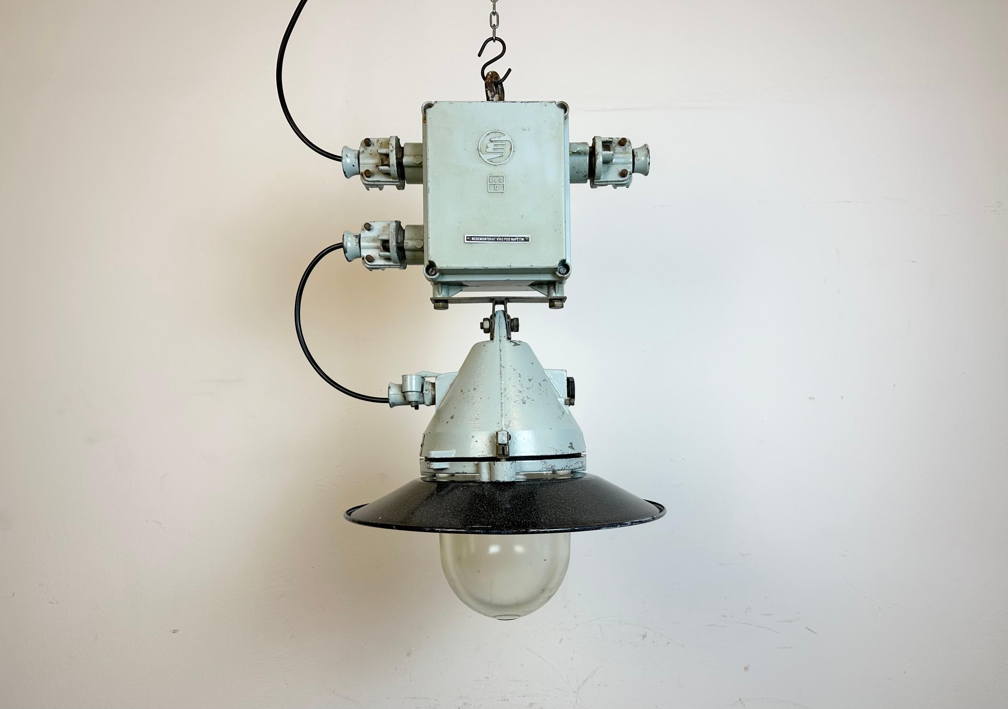 Grey industrial lamp with massive protective glass bulb made by Elektrosvit in former Czechoslovakia during the 1970s.It features a grey cast aluminium body, a clear glass and a grey enameled shade with white interior. Porcelain socket requires