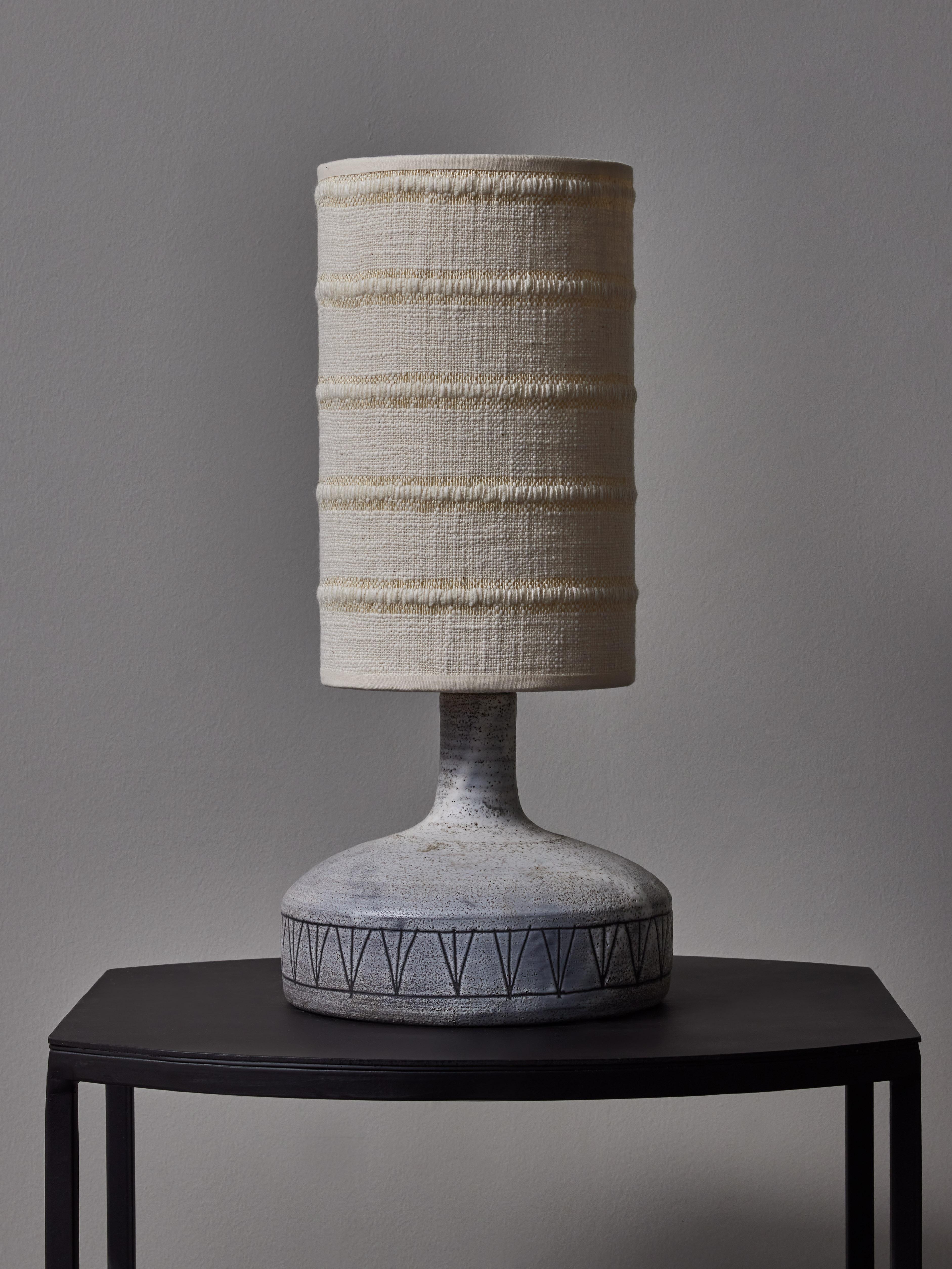 Small ceramic table lamp with a mat light grey glaze and scared decors by Jacques Pouchain signed at the bottom L’Atelier Dieulefit. Topped with a shade with Dedar Milano fabric.


Jacques Pouchain (1927-2015)
Painter, sculptor and ceramist, best
