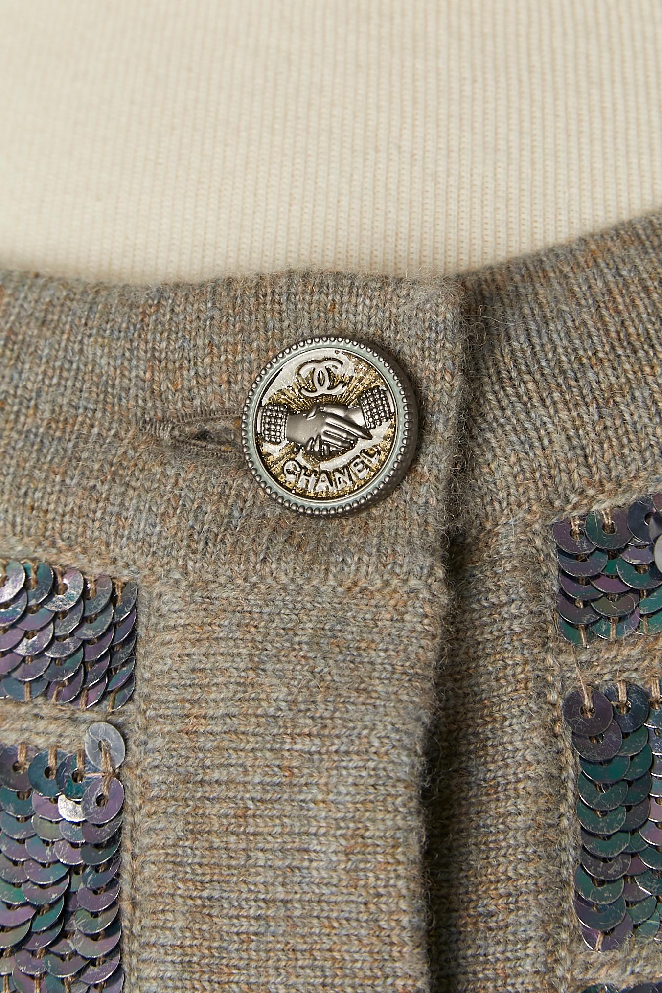 Grauer Chiné-Kaschmir-Cardigan mit silberner Polyester-Paillettenverzierung. Markenknopf und Knopflochverschluss in der vorderen Mitte. 
SIZE 40 (Fr) M/L 