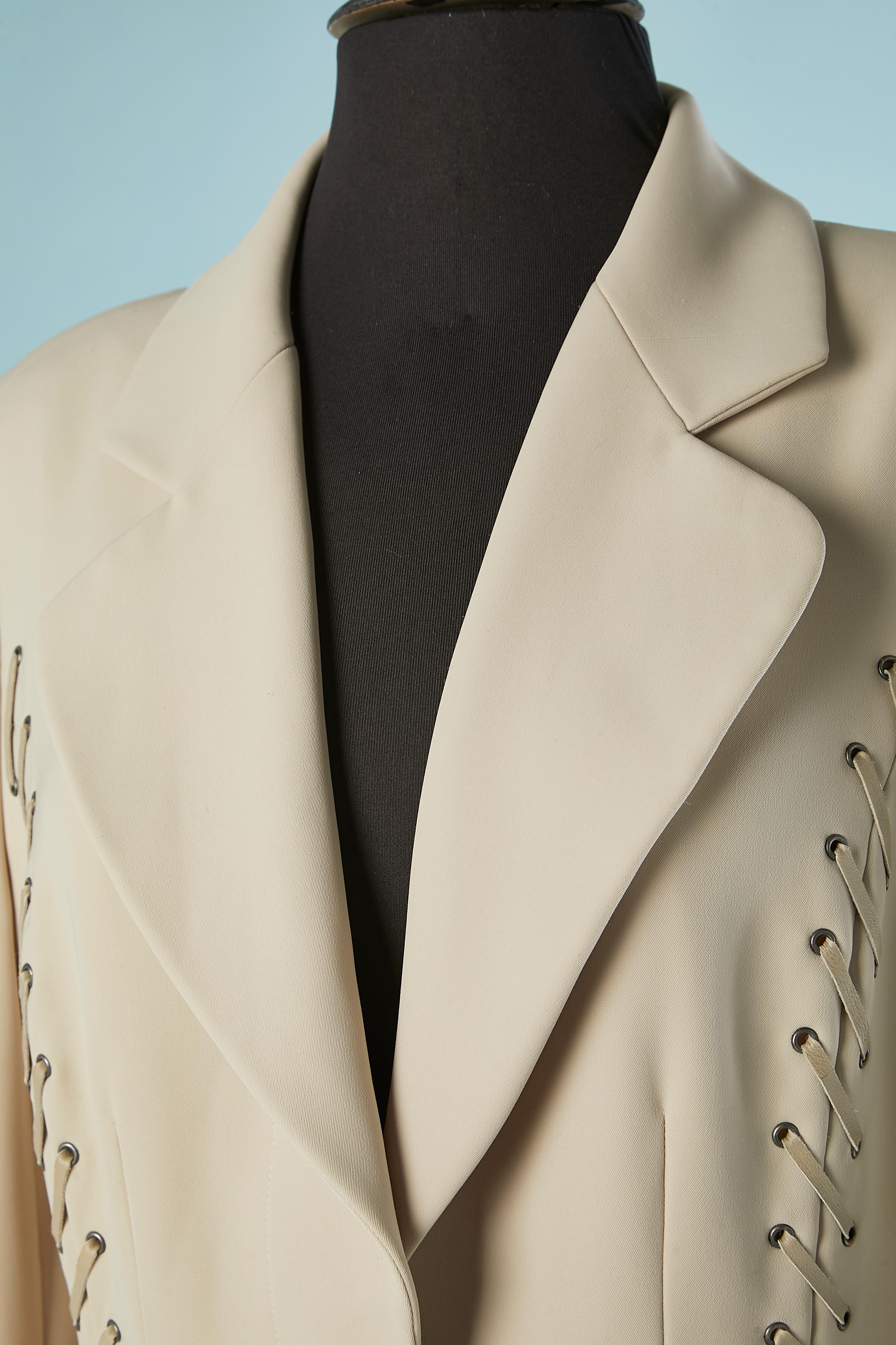 Manteau gris avec des rubans de cuir gris lacés devant et derrière.
Composition : tissu principal et doublure 100% polyester. 
3 poches sur le devant. 2 fentes dans le dos sur le côté. Épaulettes. 2 boutons au milieu du devant pour fermer le manteau