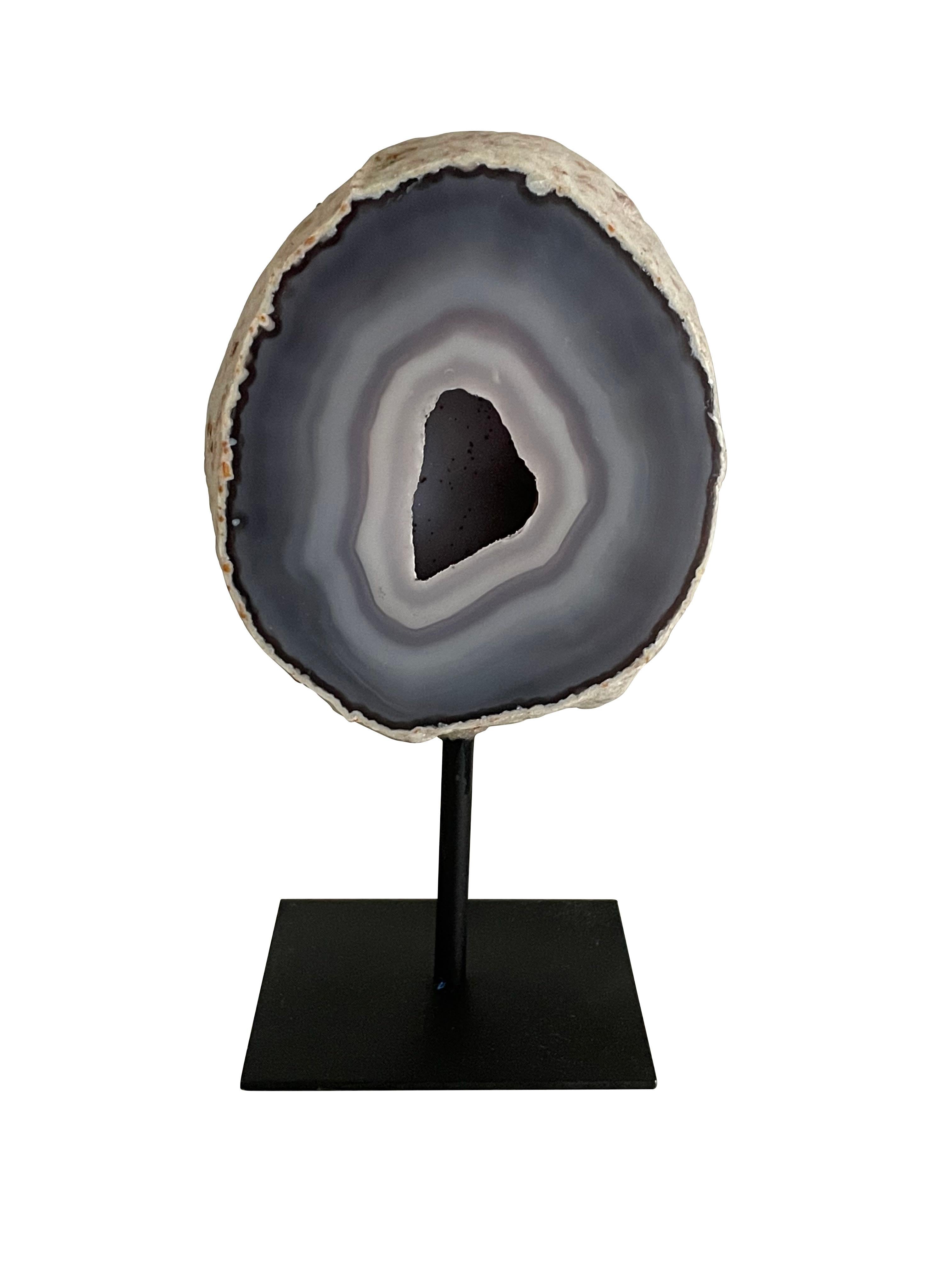 Grey Brazilian thick slice of agate mounted on a steel stand.
Agate is a banded form of finely-grained, microcrystalline Quartz. 
The lovely color patterns and banding make this translucent gemstone very unique. 
Agates can have many distinctive