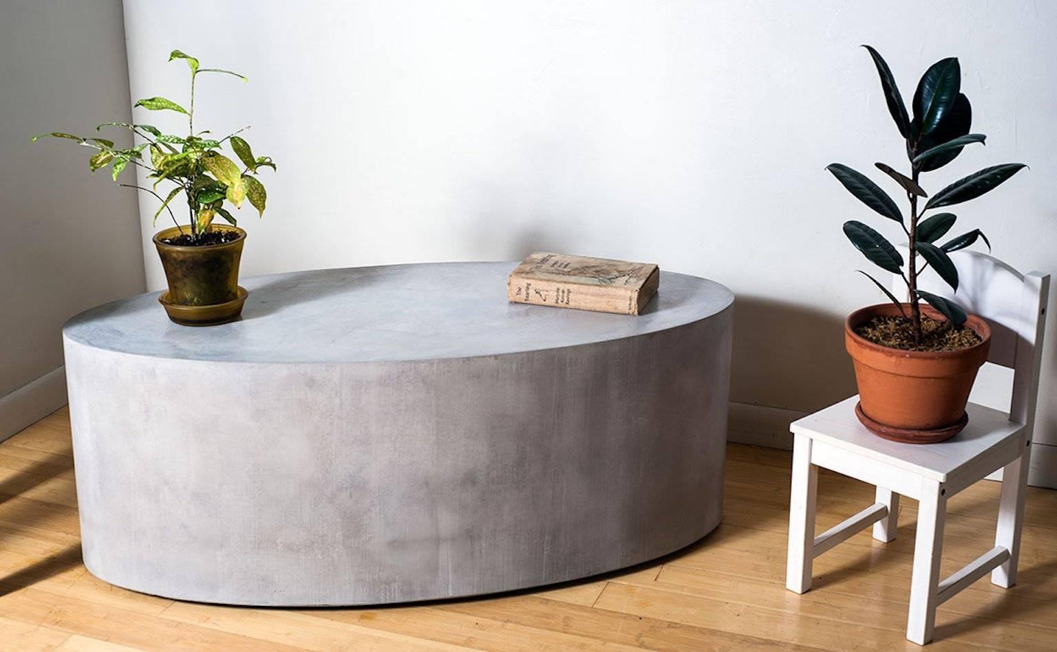 Polished concrete elliptical table with recessed casters, usable indoors and out. Cast concrete cylinder with a hollow core, hand covered in a trowel with an applied concrete finish. Available in 12 standard colors and will wear like natural stone.