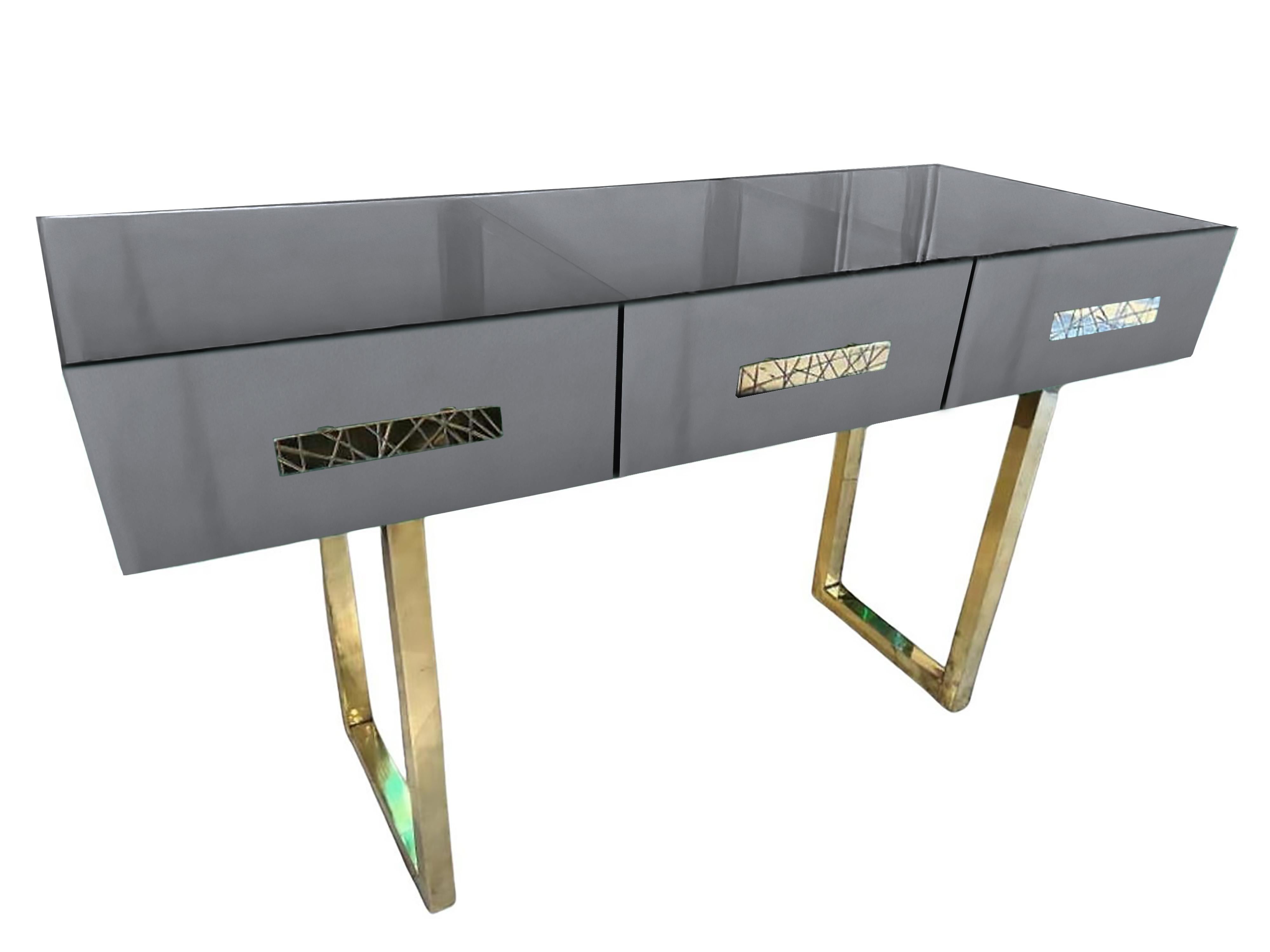 This gray console table is an eye-catching blend of modern elegance and traditional craftsmanship. 

The table is designed with three spacious drawers, each adorned with carved brass handles, adding a touch of luxury to its functionality.
In