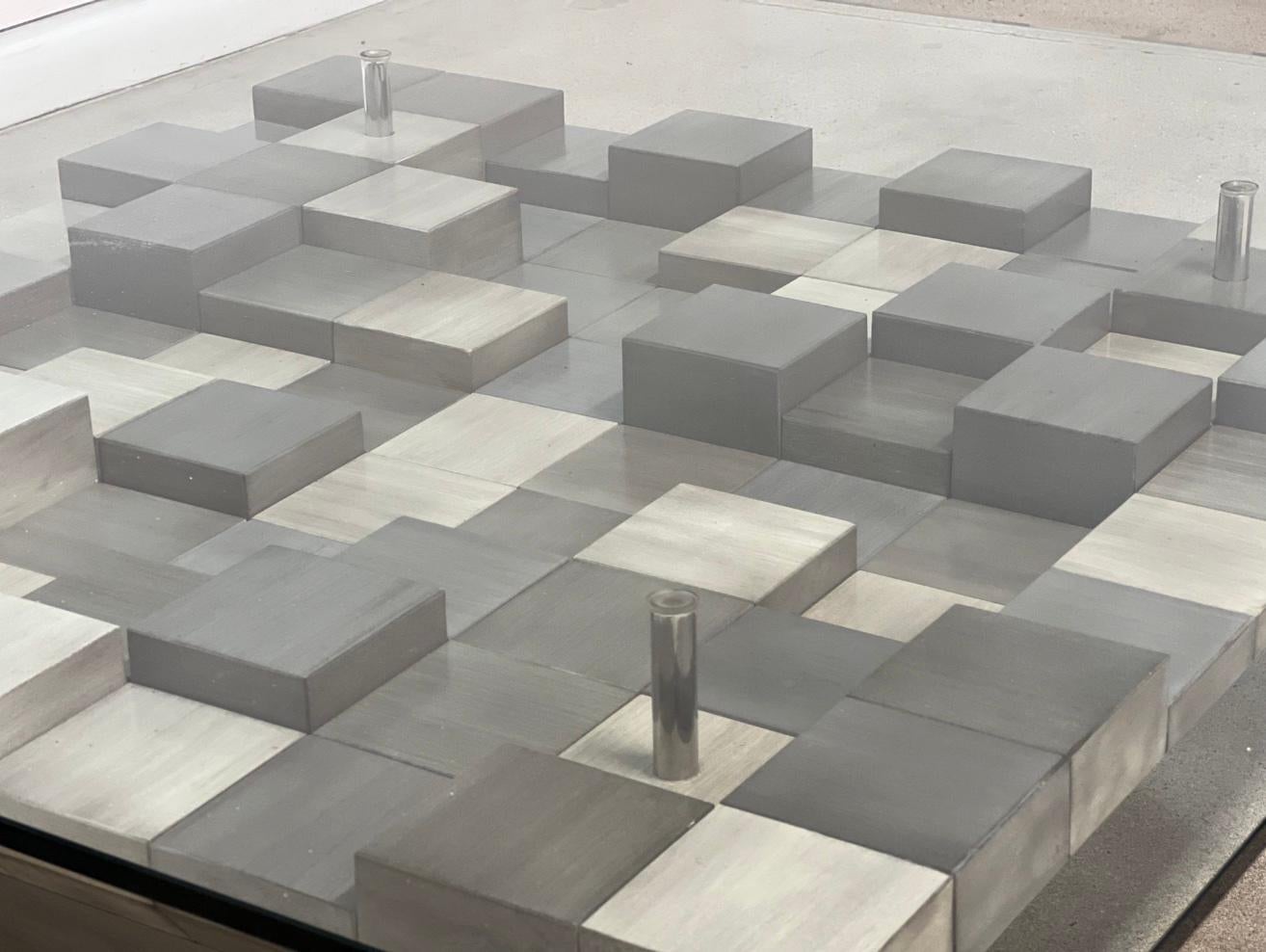 The base of this glass-top table is crafted from an intriguing combination of woods and stainless steel, forming captivating geometric shapes. This unconventional design adds a distinctiveness to the piece, making it truly remarkable. The use of