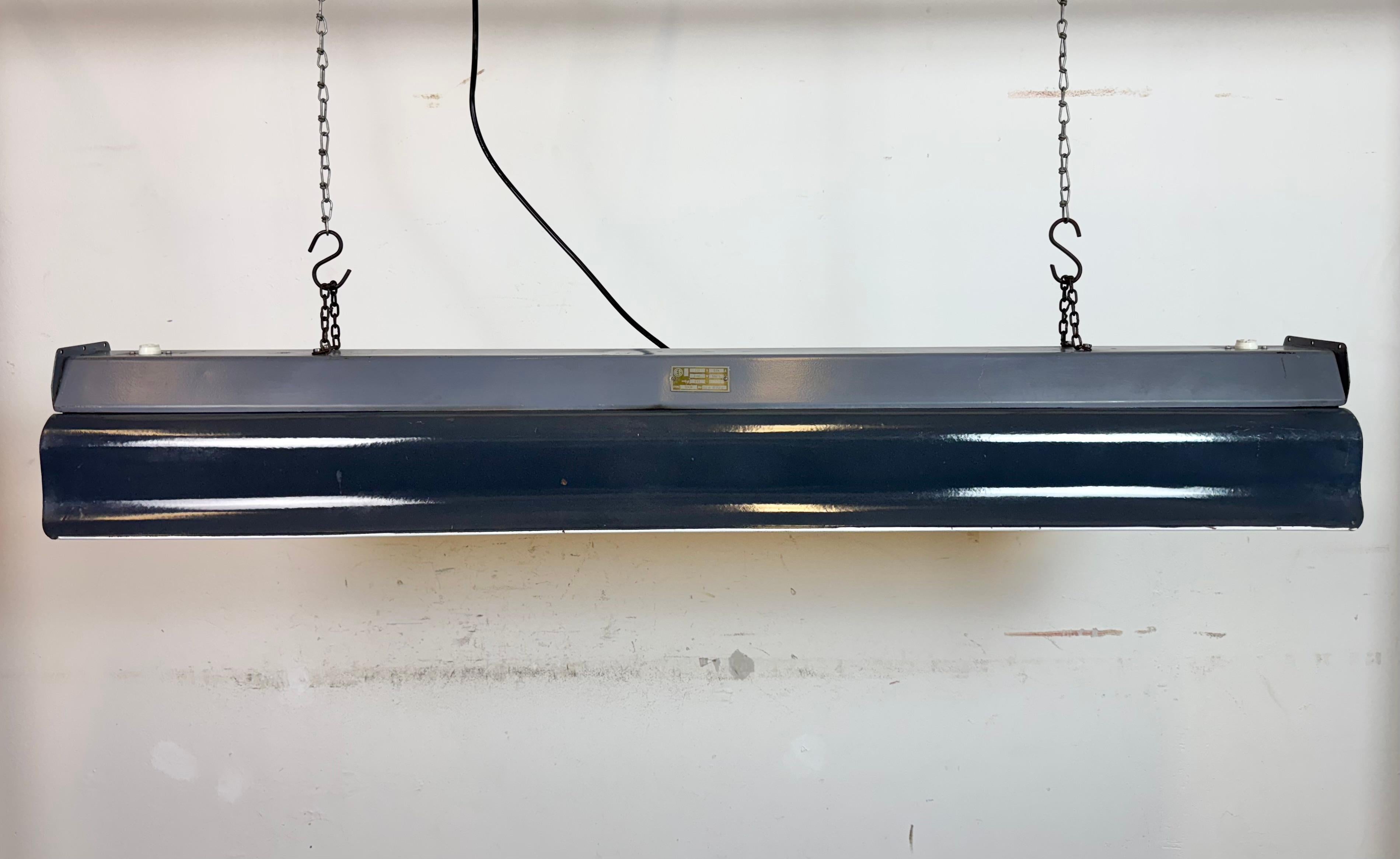 This industrial tube light was made by Elektrosvit in fot er Czechoslovakia during the 1960s. It features a dark grey enamel shade with white enamel inerrior and iron top .The light is converted into two LED T8, 120 cm light tubes. The weight of the