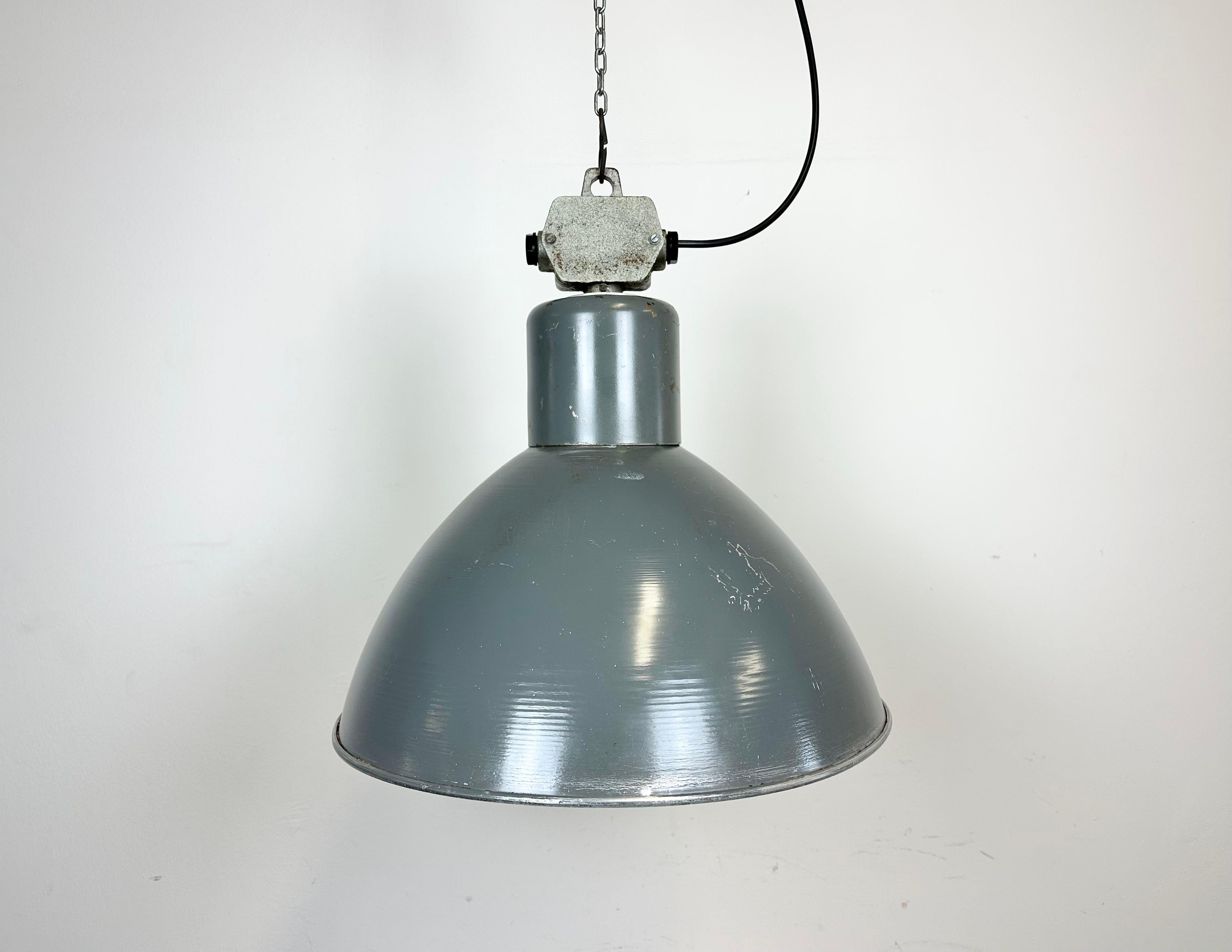 This industrial factory pendant lamp was made by Polam Wilkasy in Poland during the 1960s. It features a dark grey aluminium body and light grey cast aluminium top box. New porcelain socket requires E27/ E26 light bulbs. New wire. The piece weighs