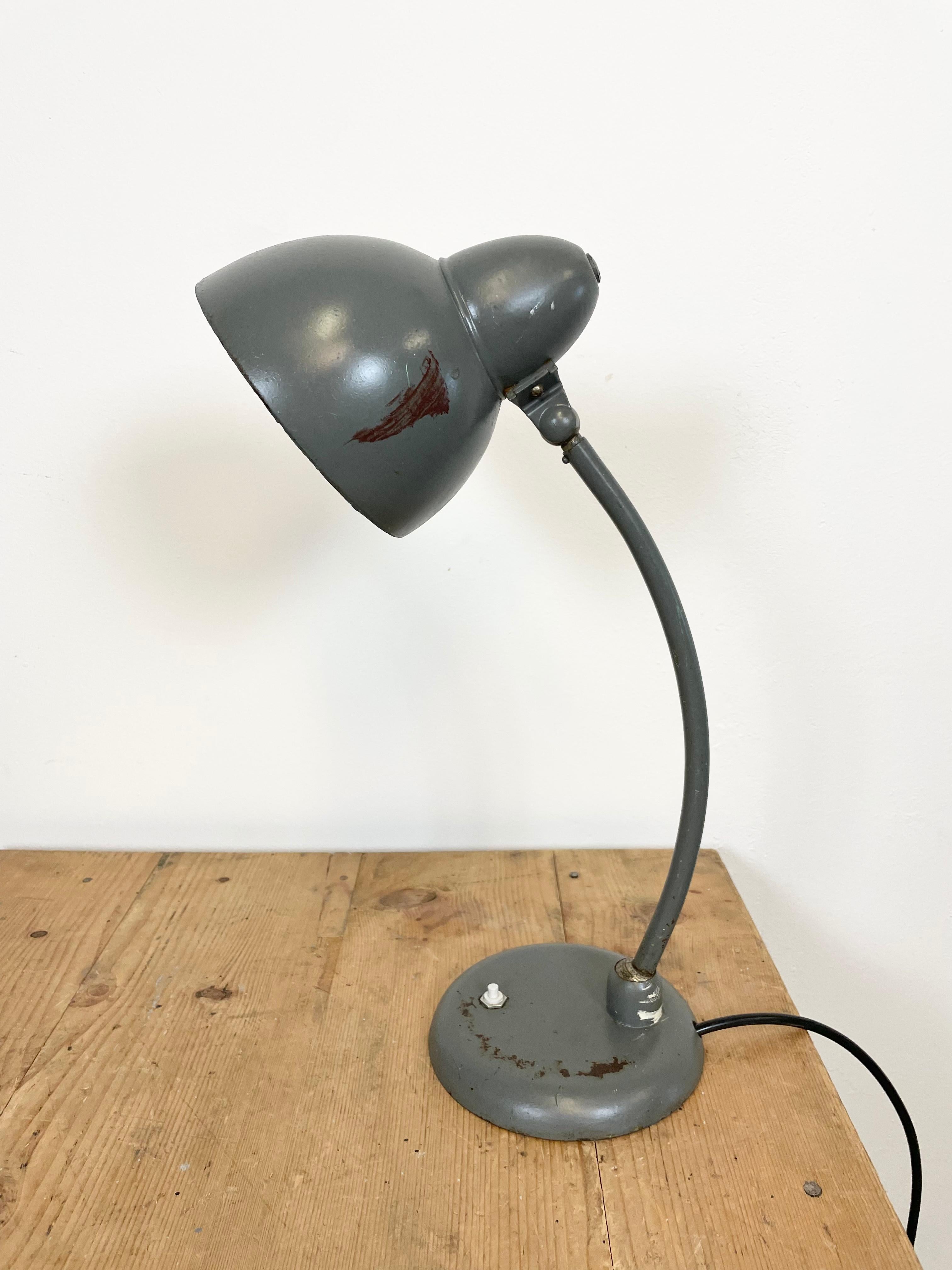 This grey Bauhaus industrial desk lamp was made in former Czechoslovakia during the 1930s. The lamp has grey metal shade, iron base and arm, two adjustable joints, porcelain socket for E 27 lightbulbs and new wire. Fully functional. Lampshade