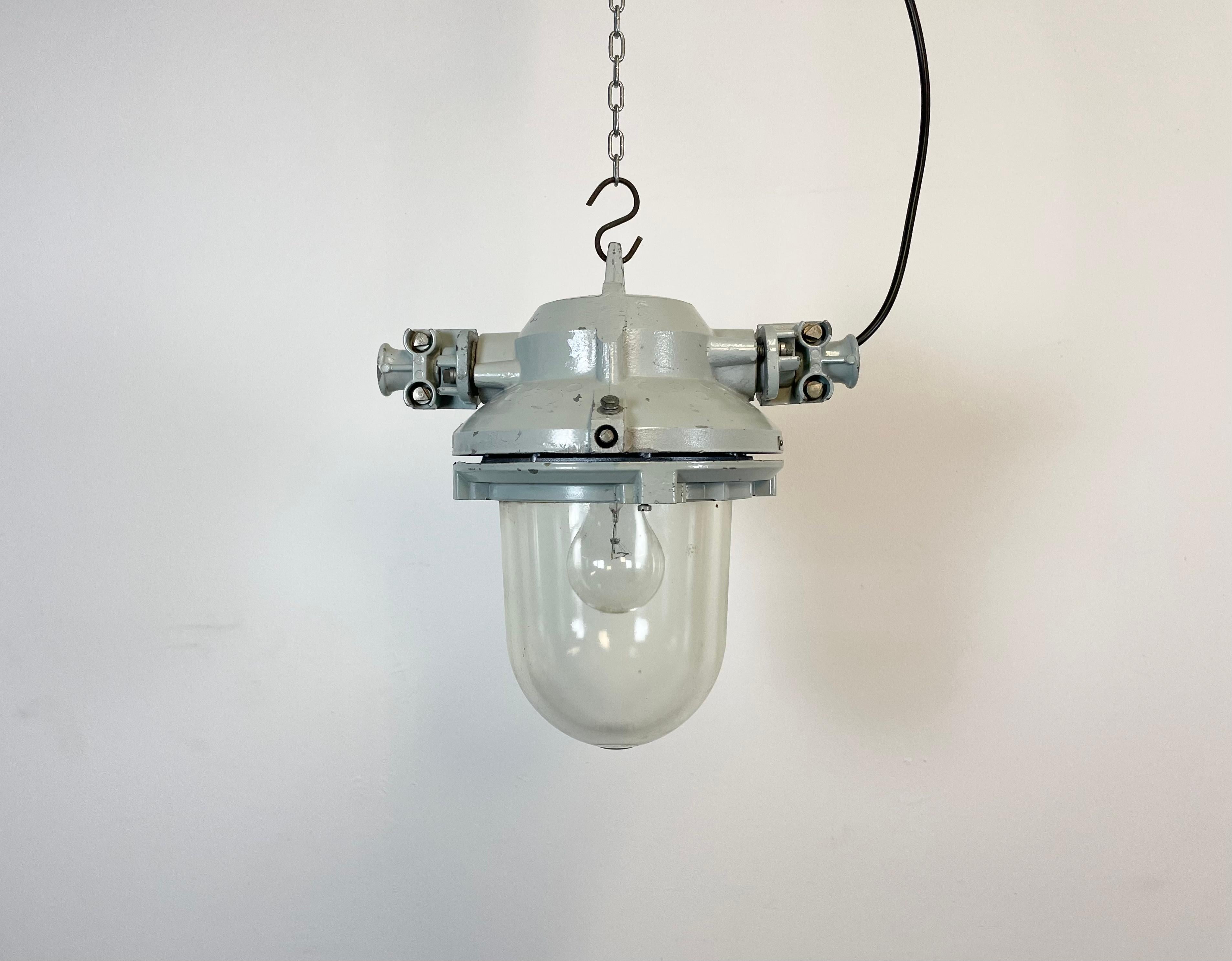 Lampe industrielle grise avec ampoule massive en verre de protection. Fabriqué en ex-Tchécoslovaquie par Elektrosvit dans les années 1970. Il présente un corps en aluminium moulé et un verre transparent. La douille en porcelaine nécessite des