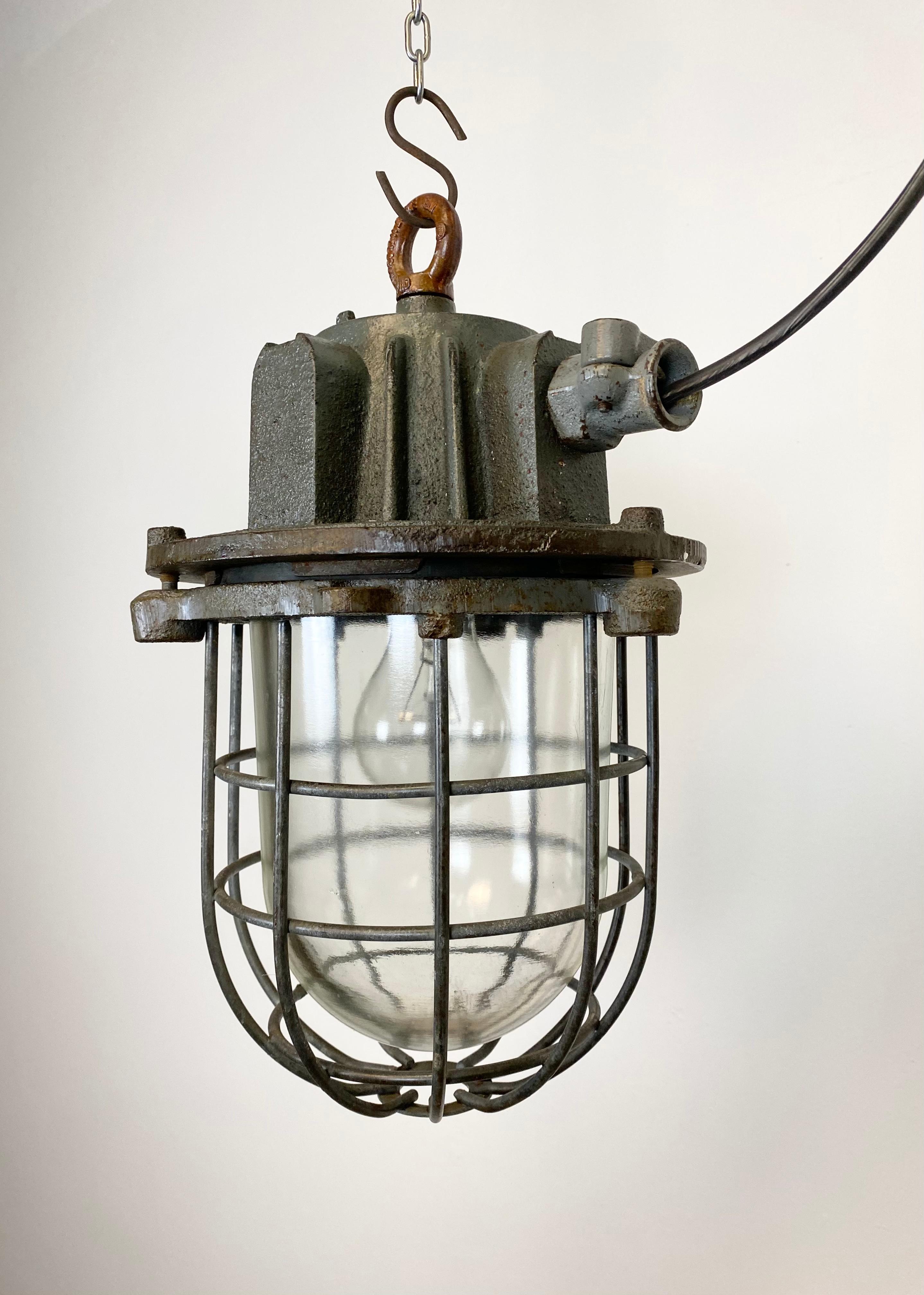 Industrial hanging lamp made in former Czechoslovakia during the 1960s. It features cast iron top, clear glass cover and iron grid. Porcelain socket for E 27 lightbulbs and new wire. The weight of the lamp is 9 kg.