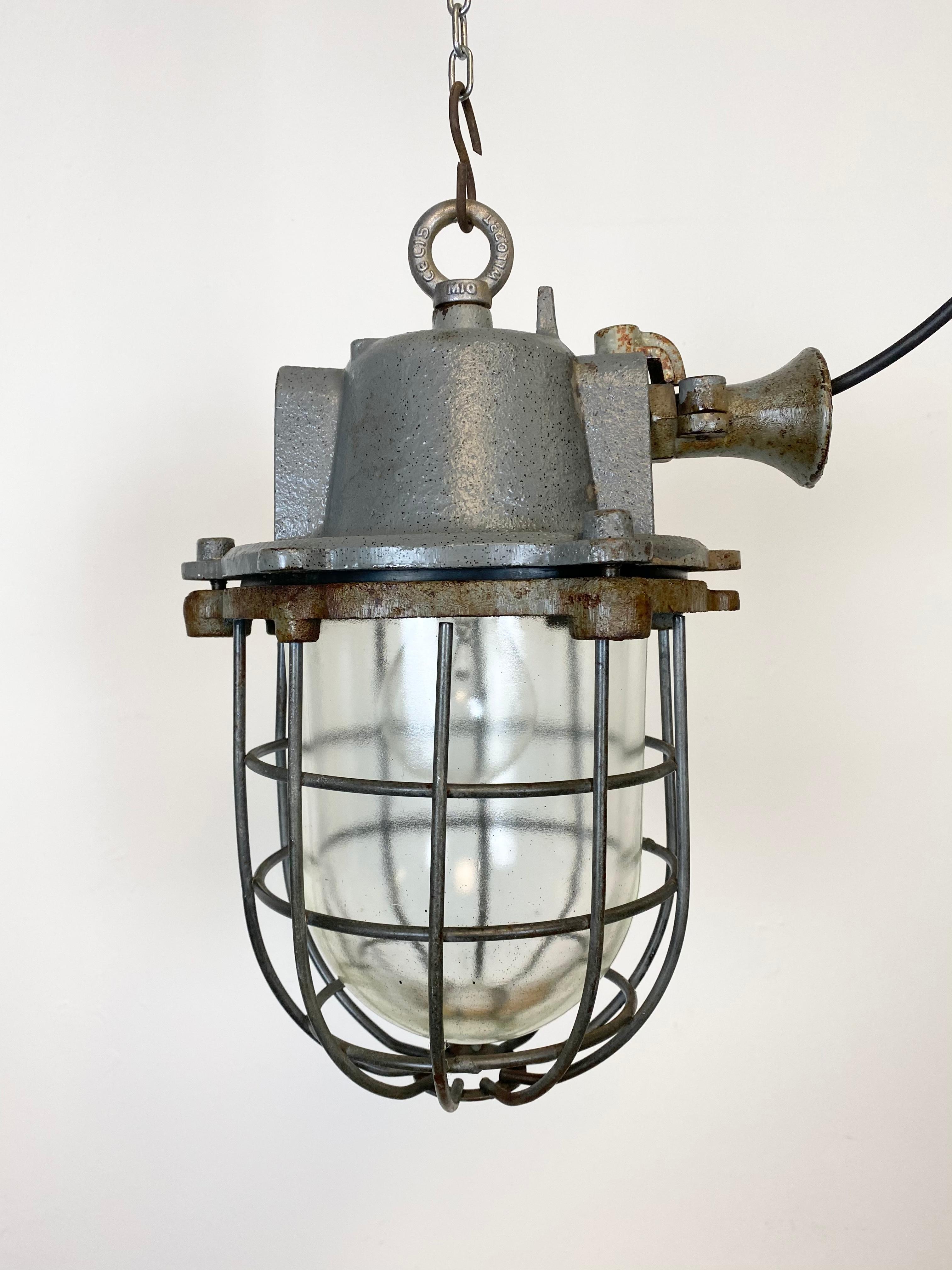 Industrial hanging lamp made in former Czechoslovakia during the 1960s. It features cast iron top, clear glass cover and iron grid. Porcelain socket for E 27 lightbulbs and new wire. The weight of the lamp is 9 kg.