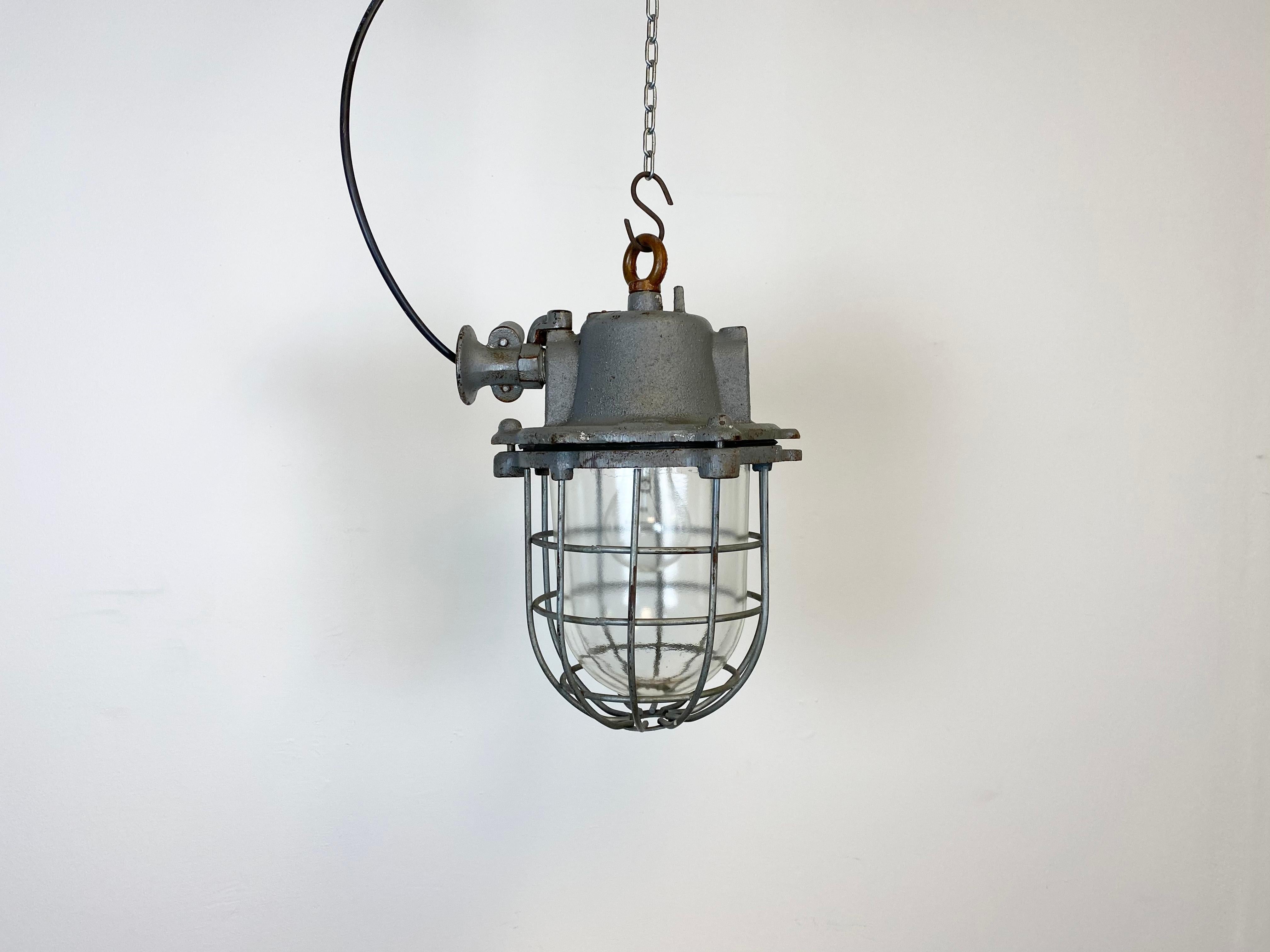 Industrial hanging lamp made in former Czechoslovakia during the 1960s. It features cast iron top, clear glass cover and iron grid. Porcelain socket for E 27 lightbulbs and new wire. The weight of the lamp is 9 kg.