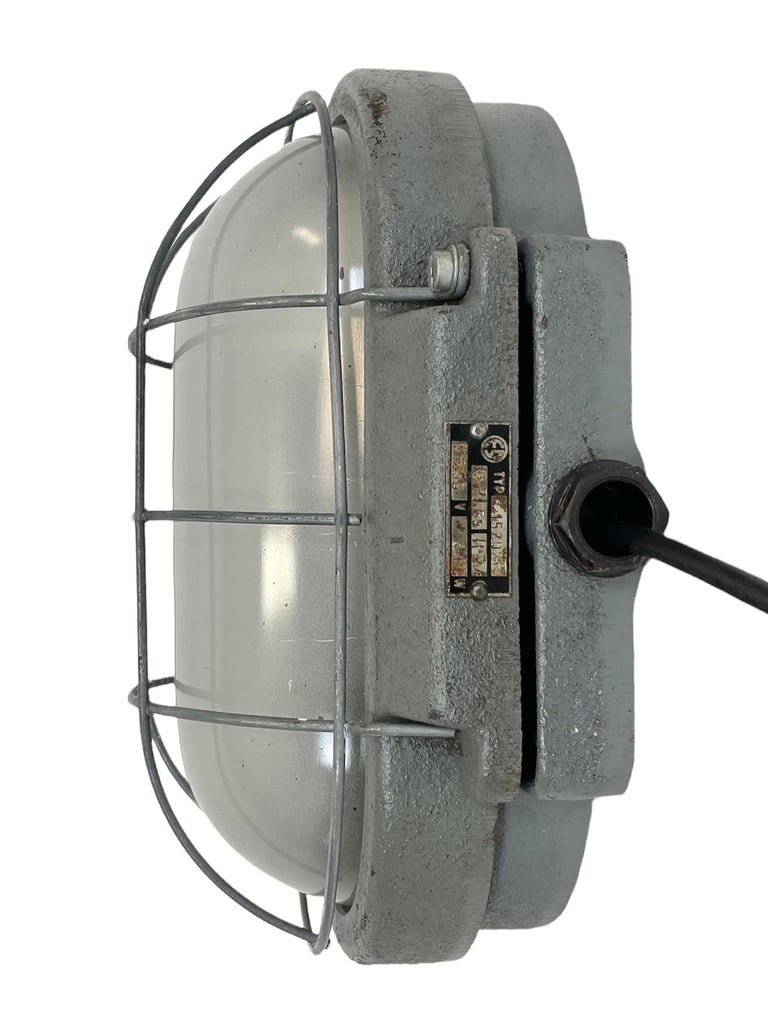 Industrial wall light made by Elektrosvit in former Czechoslovakia during the 1960s. It features a cast iron body, a milk glass cover and a steel grid.The porcelain socket requires E 27 light bulbs. New wire. The weight of the light is 5 kg.
