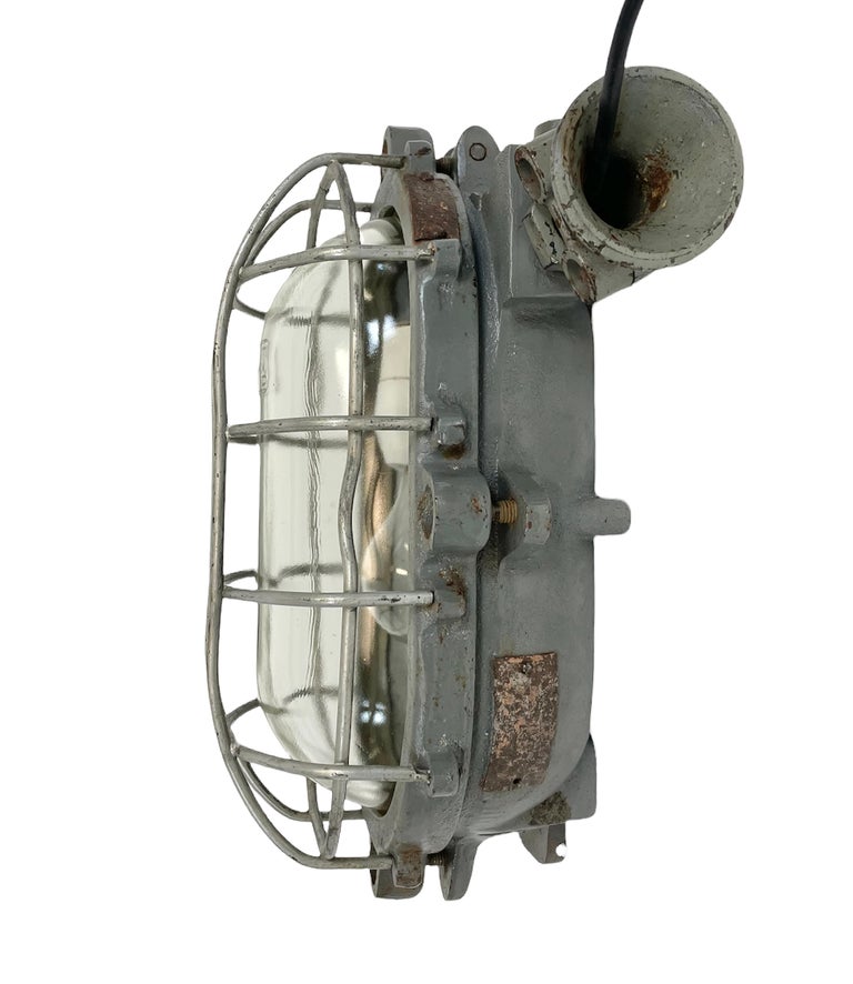 Industrial wall light made by Elektrosvit in former Czechoslovakia during the 1960s. It features a cast iron body, a clear glass cover and a steel grid.The porcelain socket requires E 27 light bulbs. New wire. The weight of the light is 7 kg.