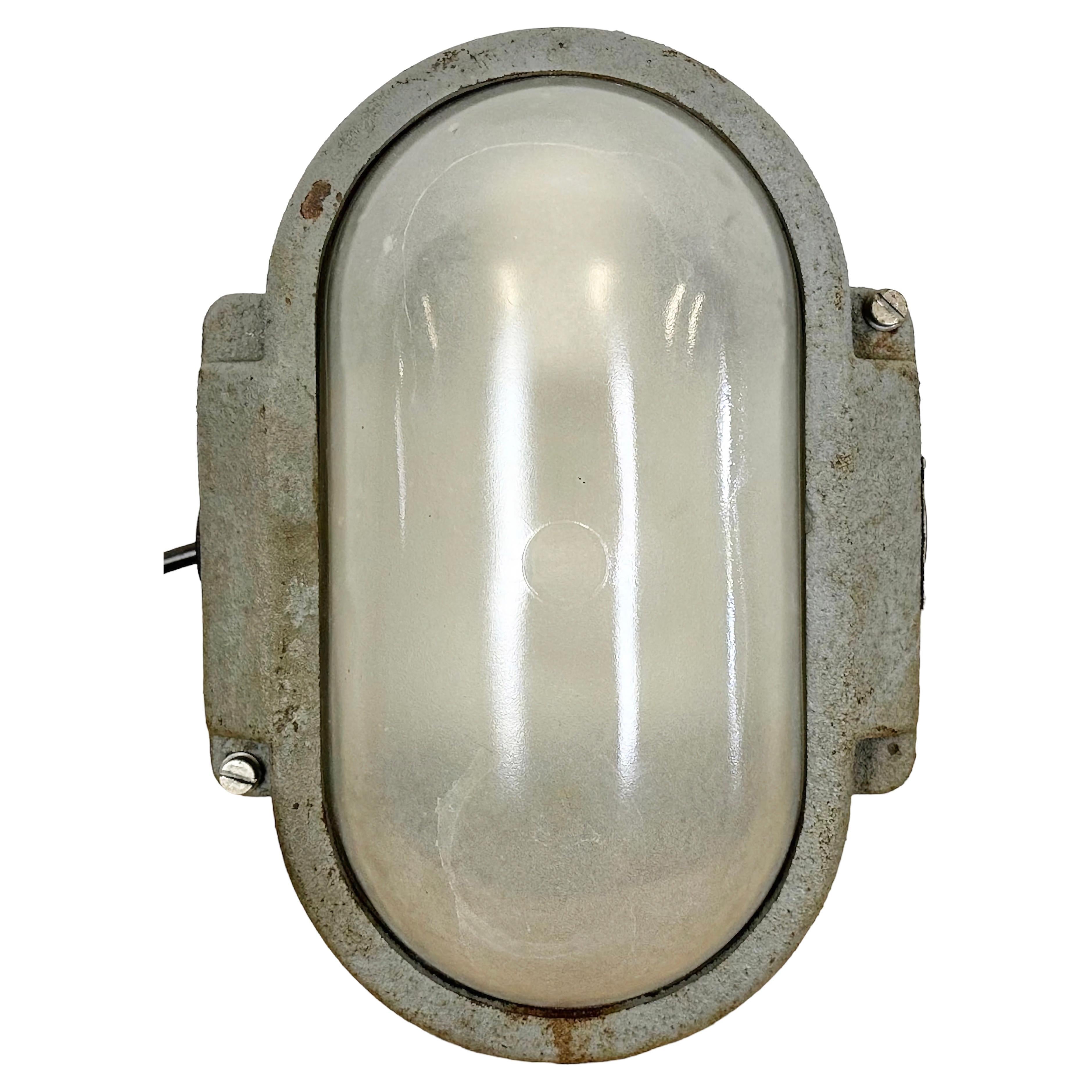 Industrial wall light made by Elektrosvit in former Czechoslovakia during the 1960s. It features a cast iron body and a milk glass cover. The porcelain socket requires E 27/ E26 light bulbs. New wire. The weight of the light is 5 kg.