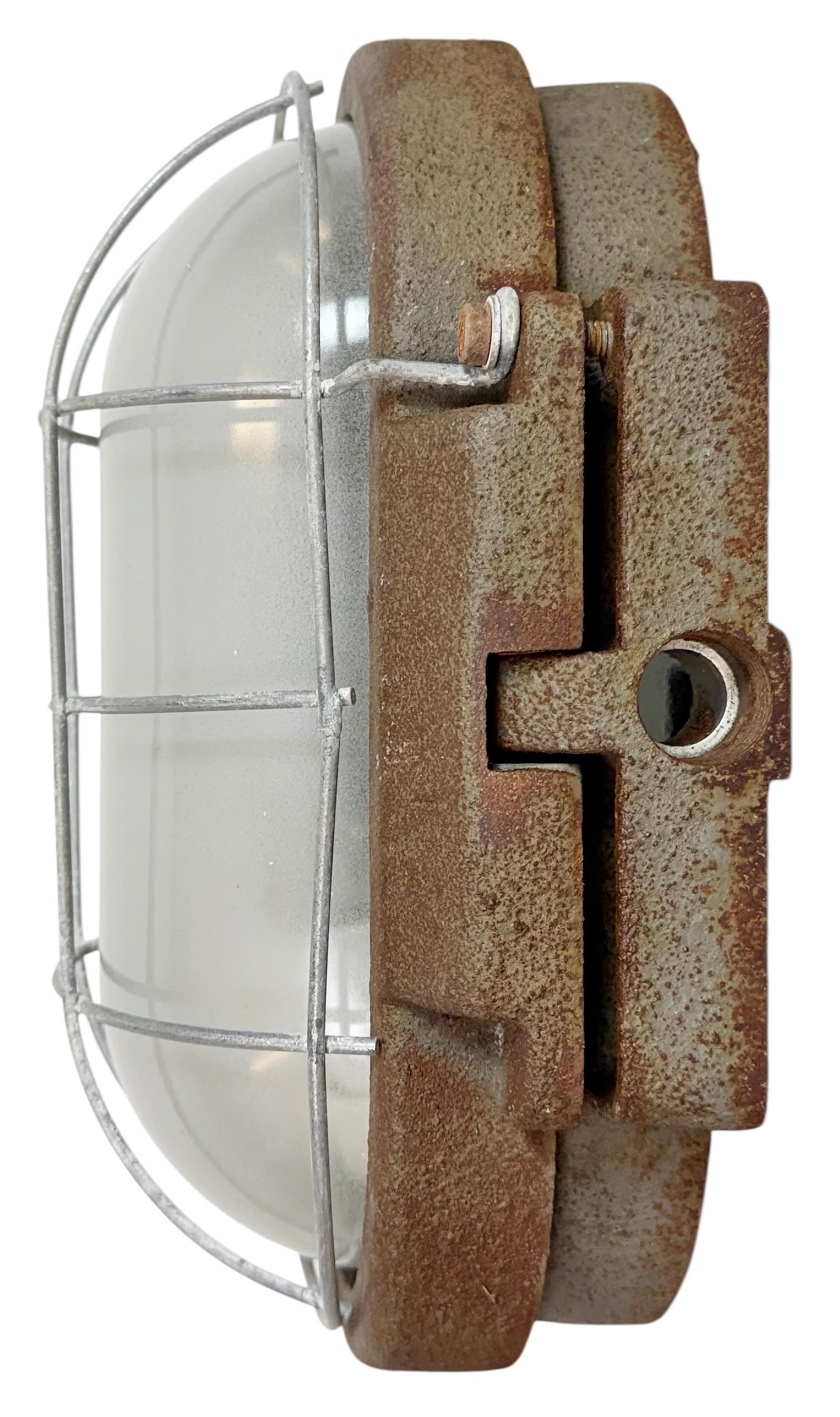 Industrielle Wandleuchte, hergestellt von Elektrosvit in der ehemaligen Tschechoslowakei in den 1960er Jahren. Die Leuchte besteht aus einem Gusseisenkörper, einer Milchglasabdeckung und einem Eisengitter und ist mit einer Porzellanfassung für