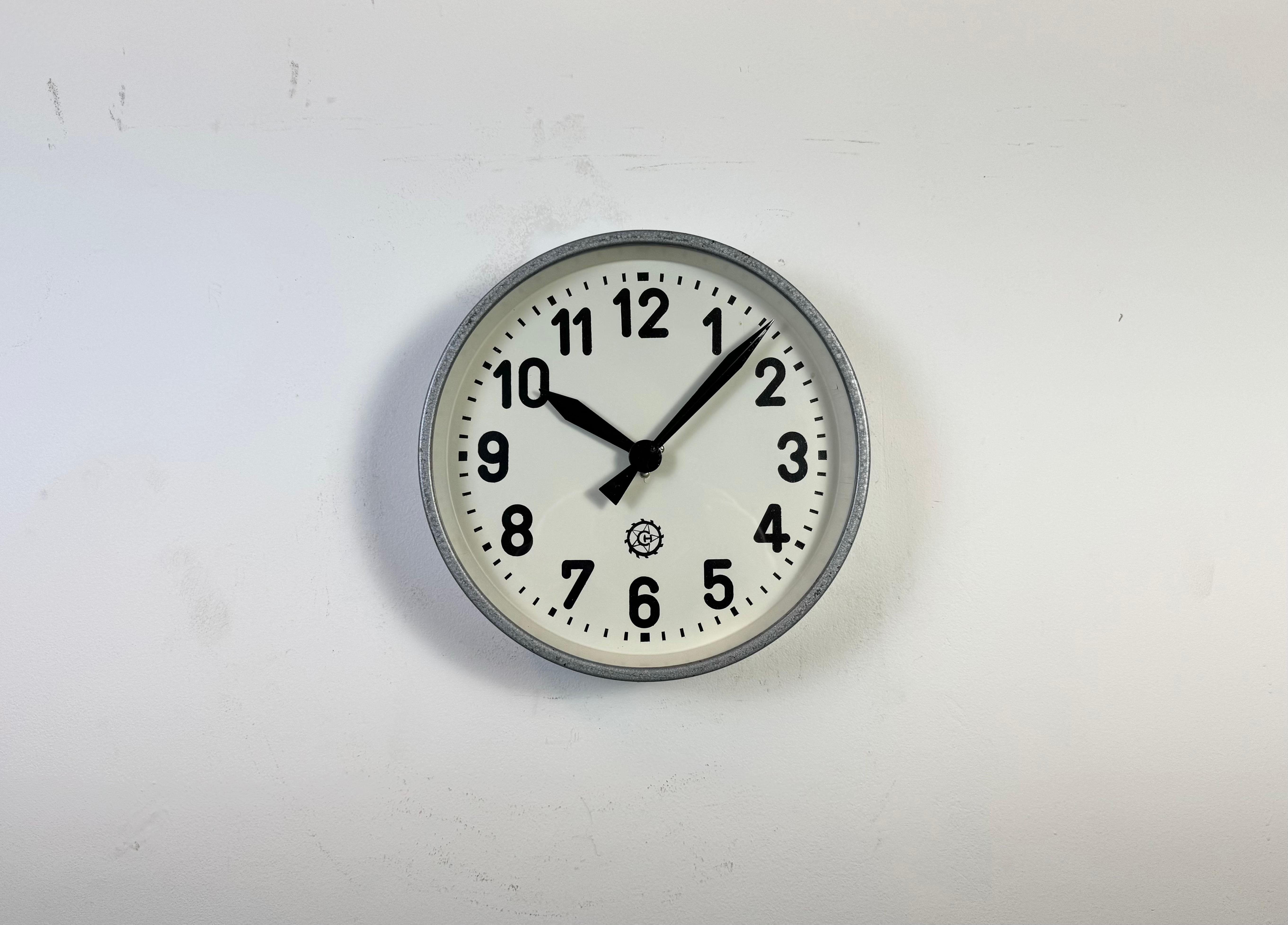 Cette horloge murale a été produite par Chronotechna dans l'ancienne Tchécoslovaquie au cours des années 1950. Elle est dotée d'un cadre et d'un fond en métal peint au marteau gris, d'un cadran en fer, d'aiguilles en aluminium et d'un couvercle en