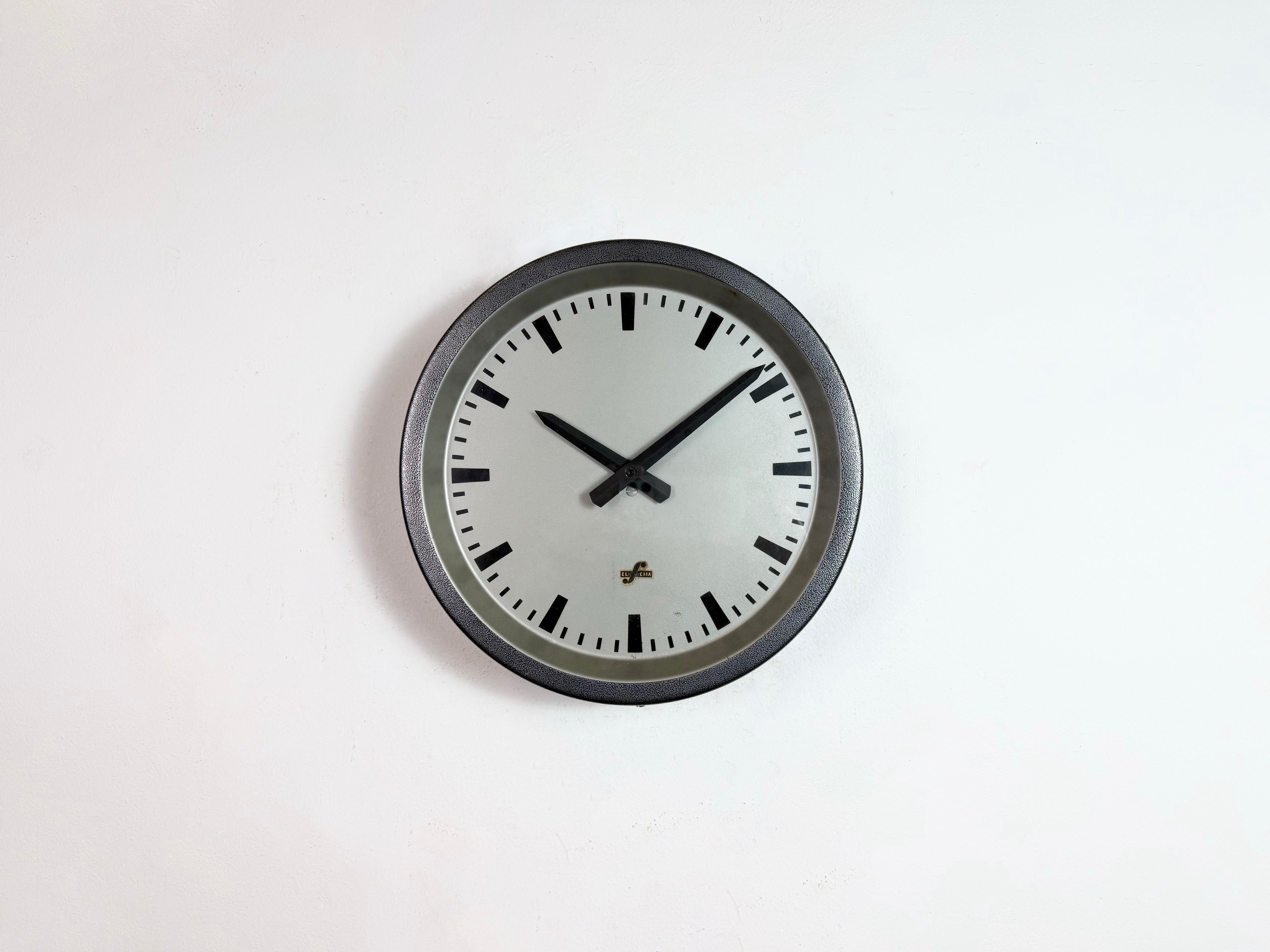 This wall clock was produced by Elfema (Electro-Mechanics Mittweida) in East Germany during the 1960s. The piece features a dark grey iron frame, a metal dial and a clear glass cover. The piece has been converted into a battery-powered clockwork and