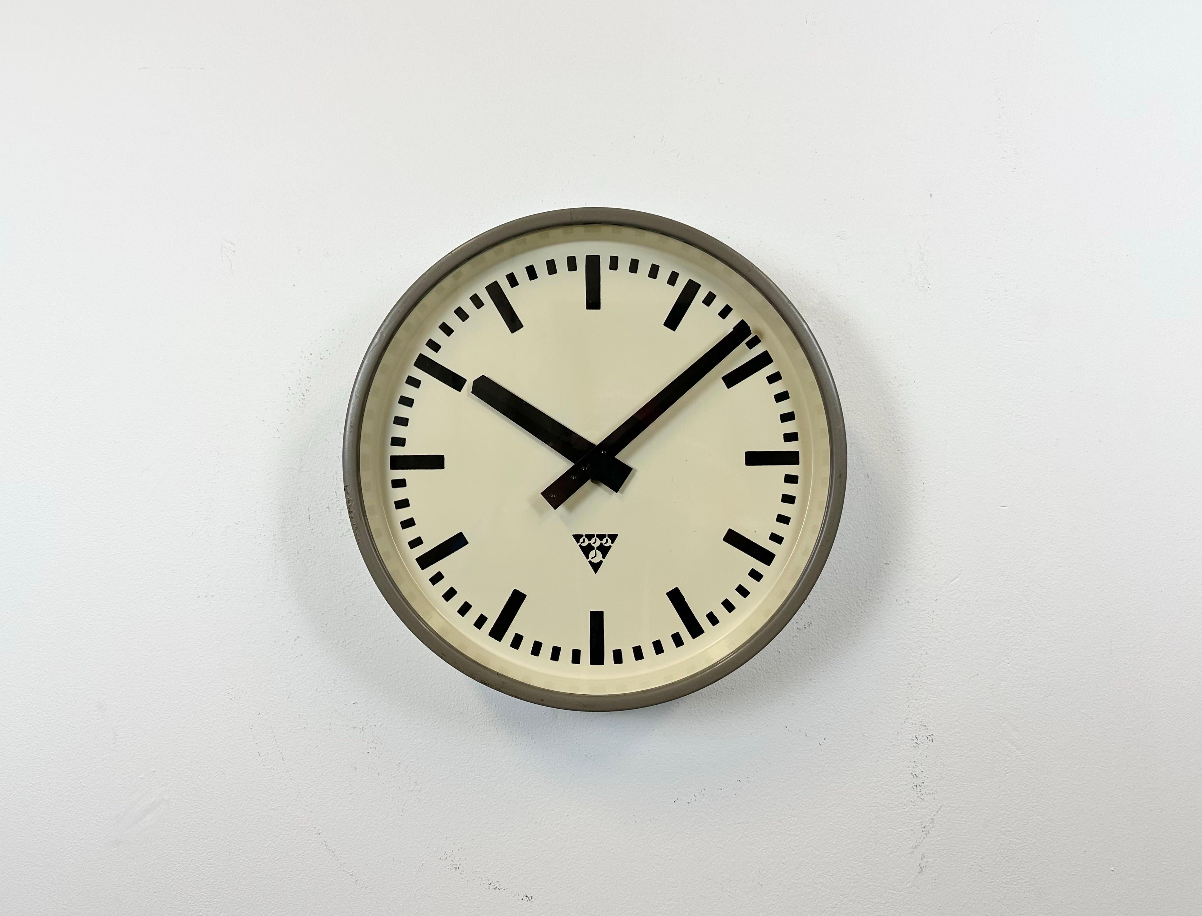 Pragotron wall clock made in former Czechoslovakia during the 1960s. It features a grey metal body, a metal dial and a clear glass cover. The piece has been converted into a battery-powered clockwork and requires only one AA-battery. The diameter of