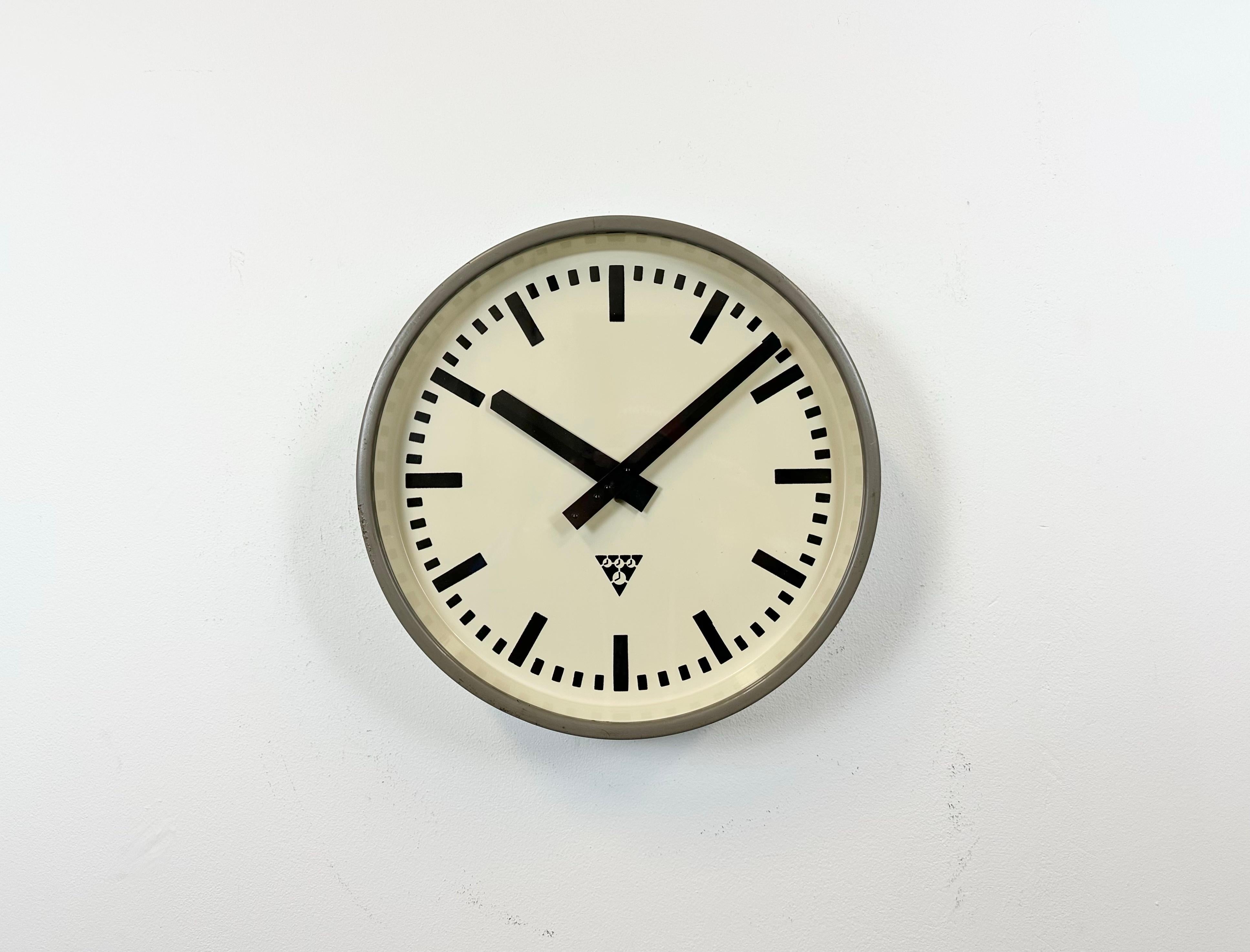 Pragotron wall clock made in former Czechoslovakia during the 1960s. It features a grey metal body, a metal dial and a clear glass cover. The piece has been converted into a battery-powered clockwork and requires only one AA-battery. The diameter of