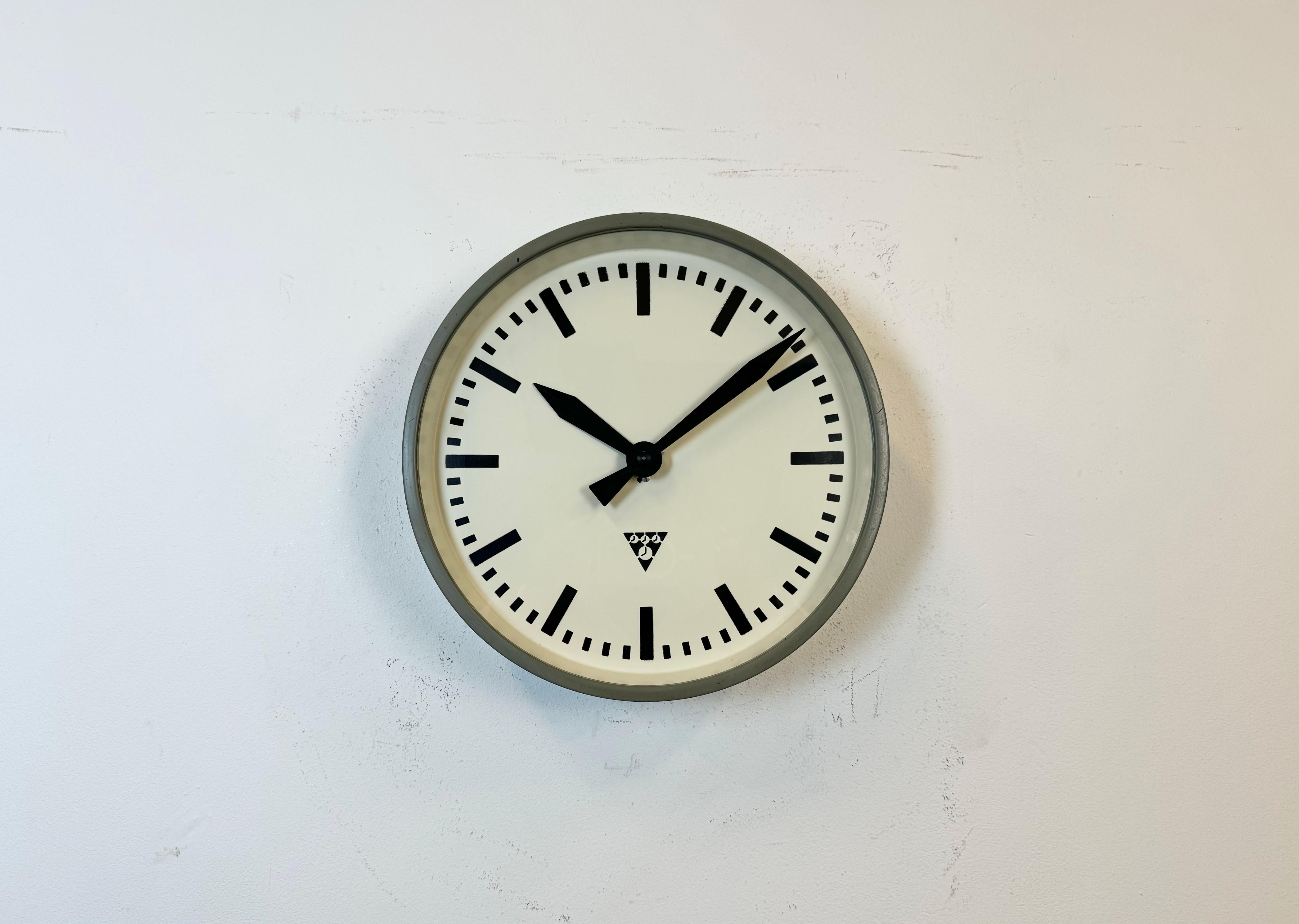 This wall clock was produced by Pragotron in former Czechoslovakia during the 1960s. It features a grey metal frame, an iron dial, an aluminium hands and a clear glass cover. Former factory slave clock has been converted into a battery-powered
