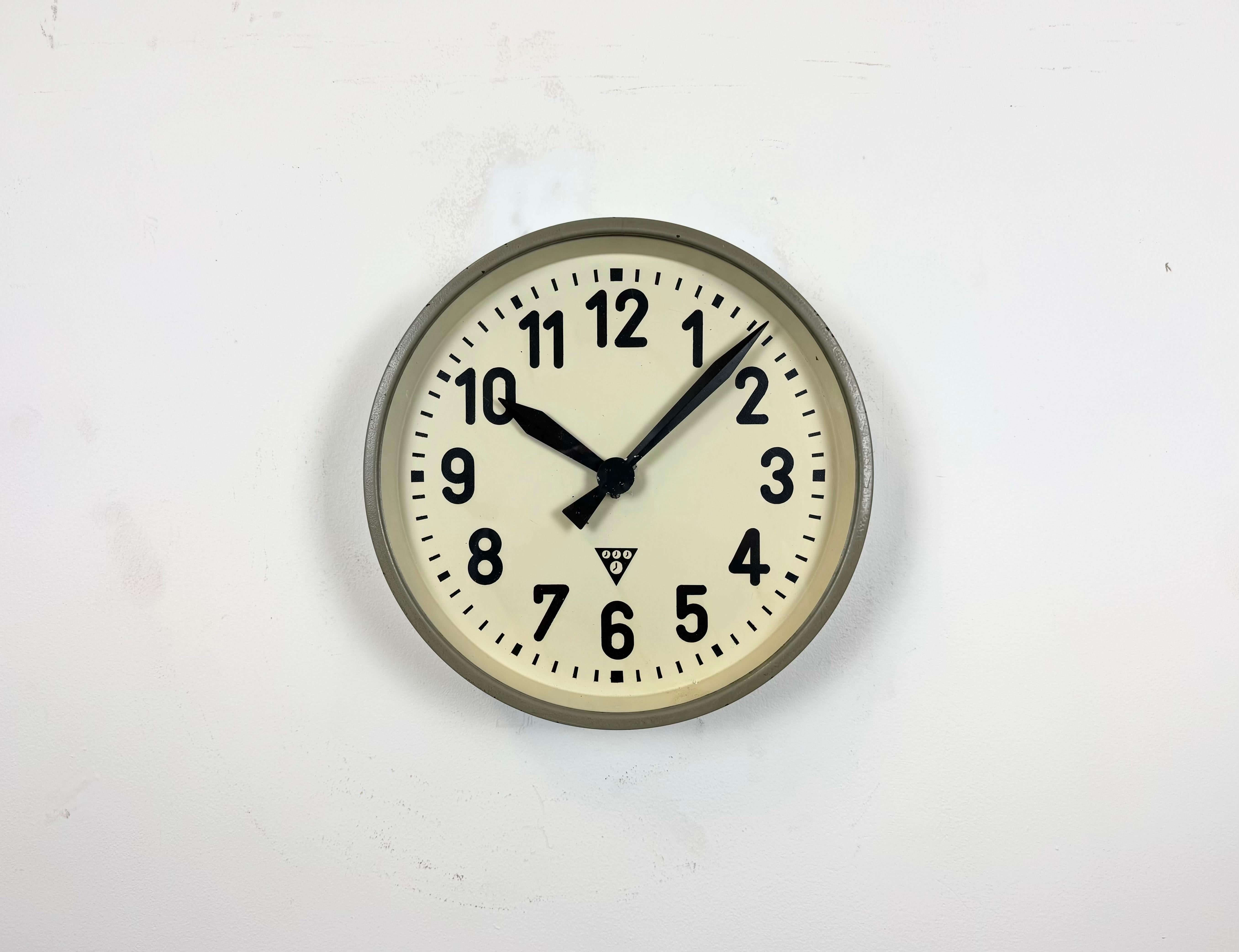 Cette horloge murale a été produite par Pragotron dans l'ancienne Tchécoslovaquie au cours des années 1960. Elle se compose d'un cadre en métal gris, d'un cadran en fer, d'aiguilles en aluminium et d'un couvercle en verre transparent. La pièce a été