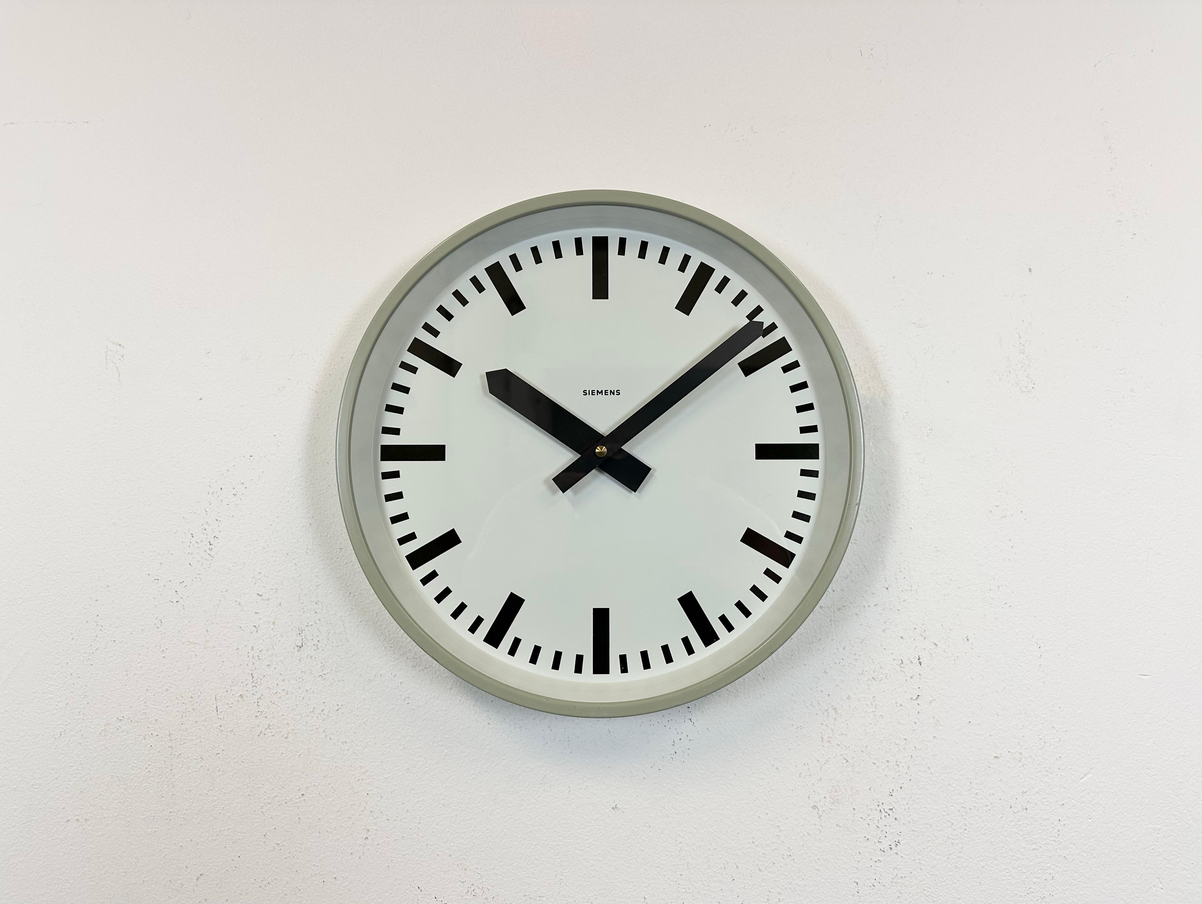 This wall clock was produced by Siemens in Germany during the 1970s. It features a grey iron frame, a metal dial and a clear glass cover. The piece has been converted into a battery-powered clockwork and requires only one AA-battery. The weight of
