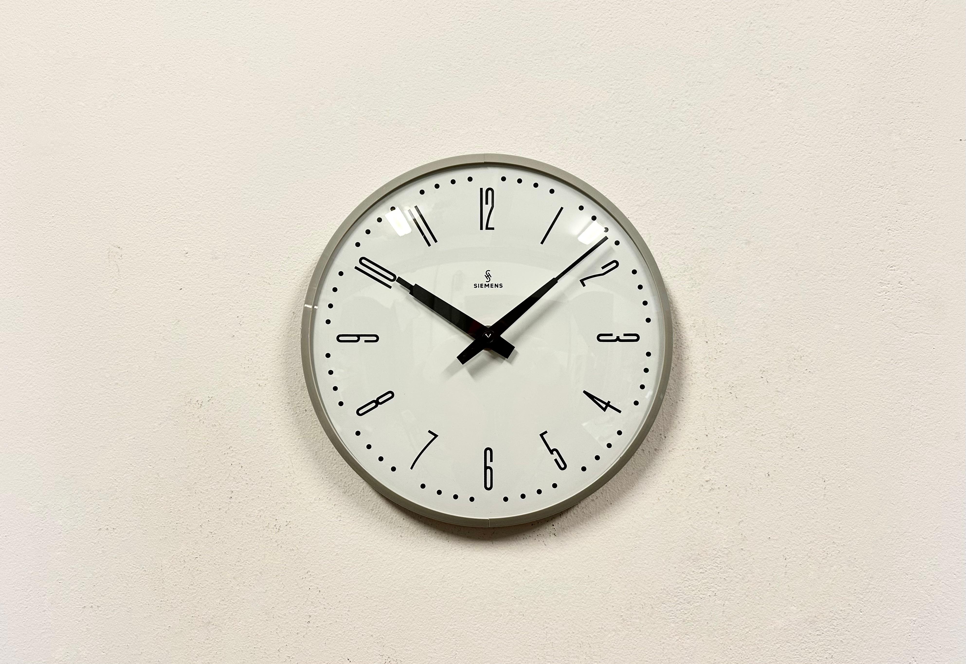 This wall clock was produced by Siemens in Germany during the 1970s. It features a grey bakelite frame, a metal dial and a convex clear glass cover. The piece has been converted into a battery-powered clockwork and requires only one AA-battery. The