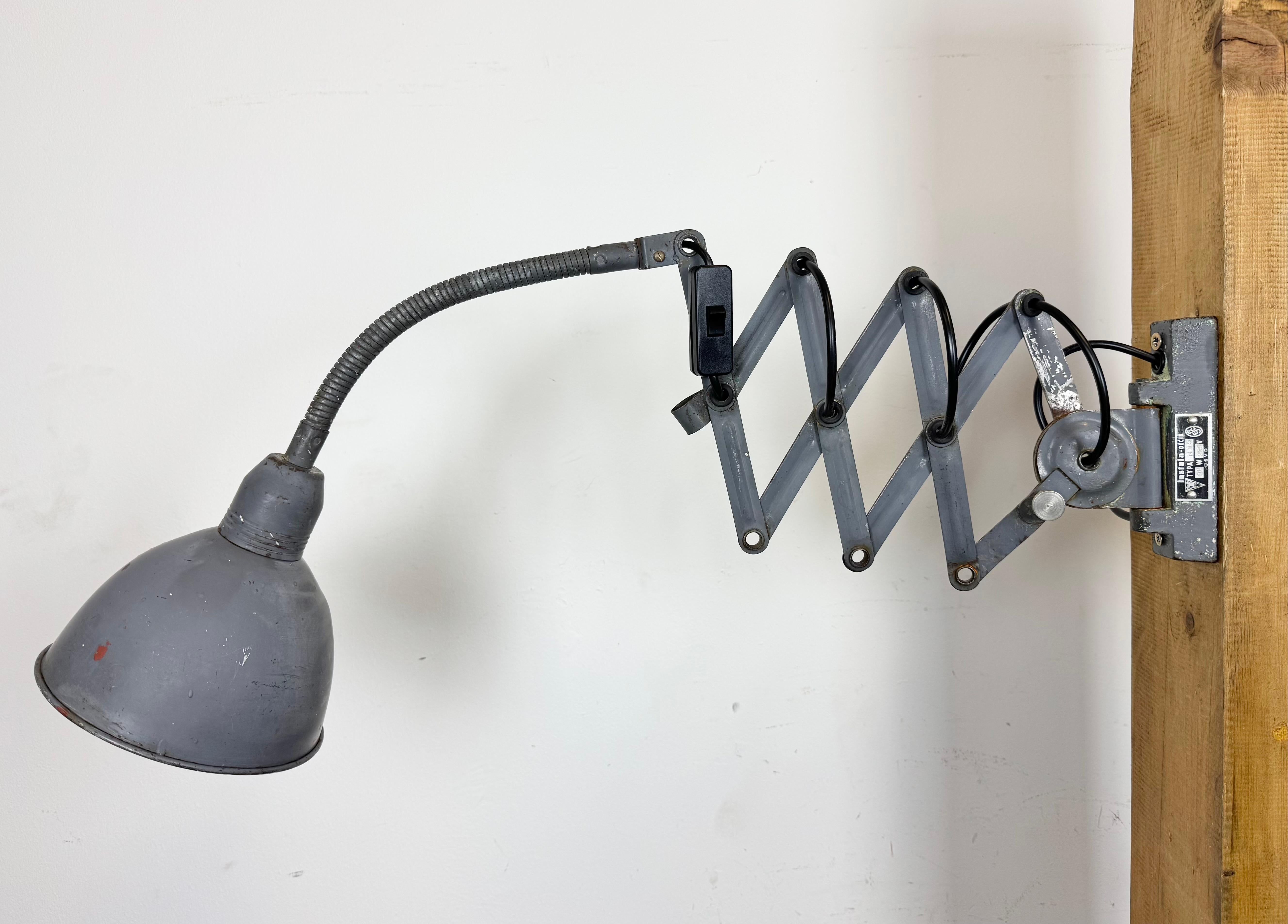 Cette applique industrielle vintage réglable à col de cygne gris a été produite par Elektroinstala Dečín dans l'ancienne Tchécoslovaquie au cours des années 1960. Elle est dotée d'un abat-jour en métal. Le bras de ciseaux en fer est extensible et
