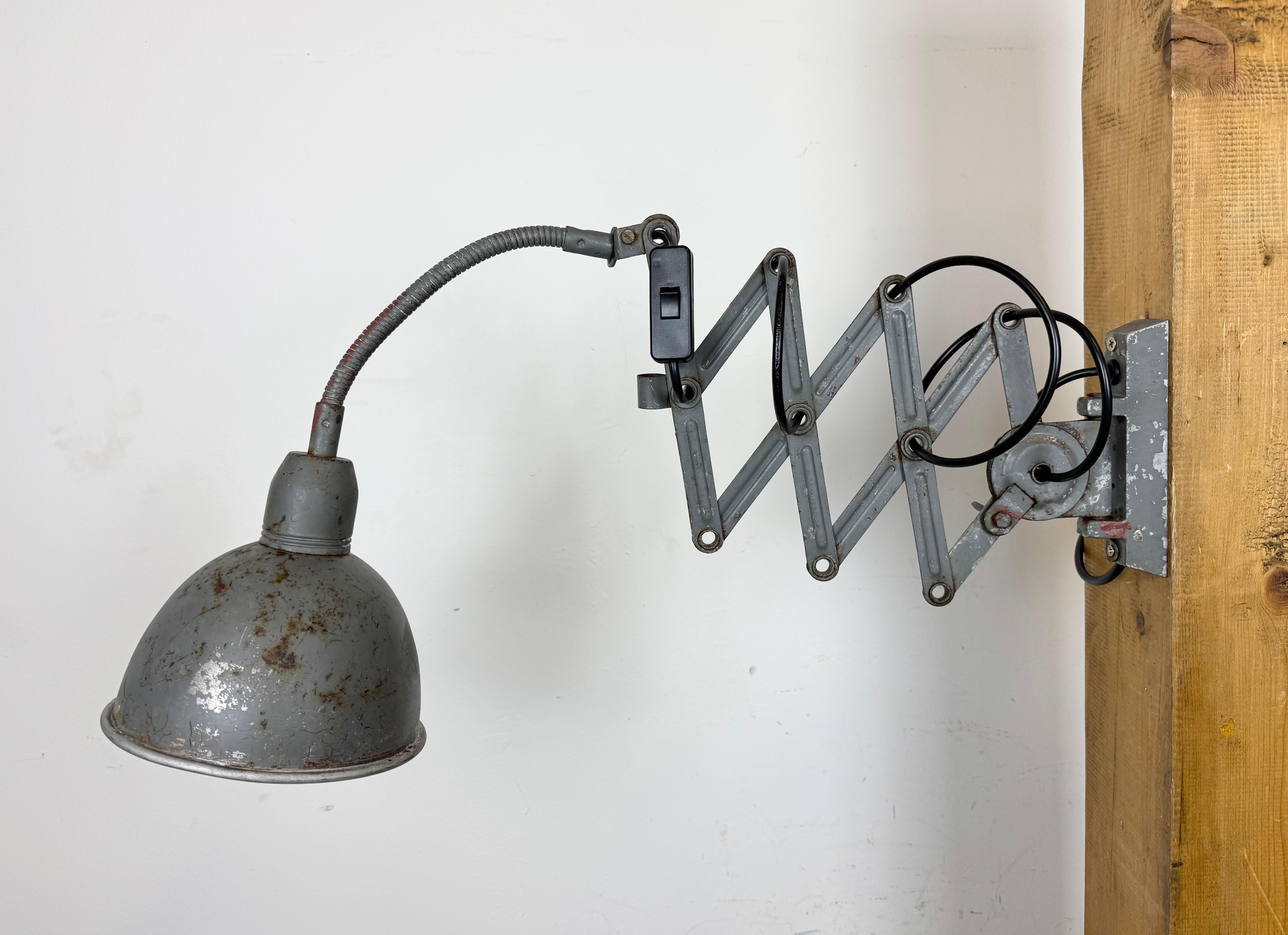 Cette applique industrielle vintage réglable à col de cygne gris a été produite par Elektroinstala Dečín dans l'ancienne Tchécoslovaquie au cours des années 1960. Elle est dotée d'un abat-jour en métal. Le bras de ciseaux en fer est extensible et