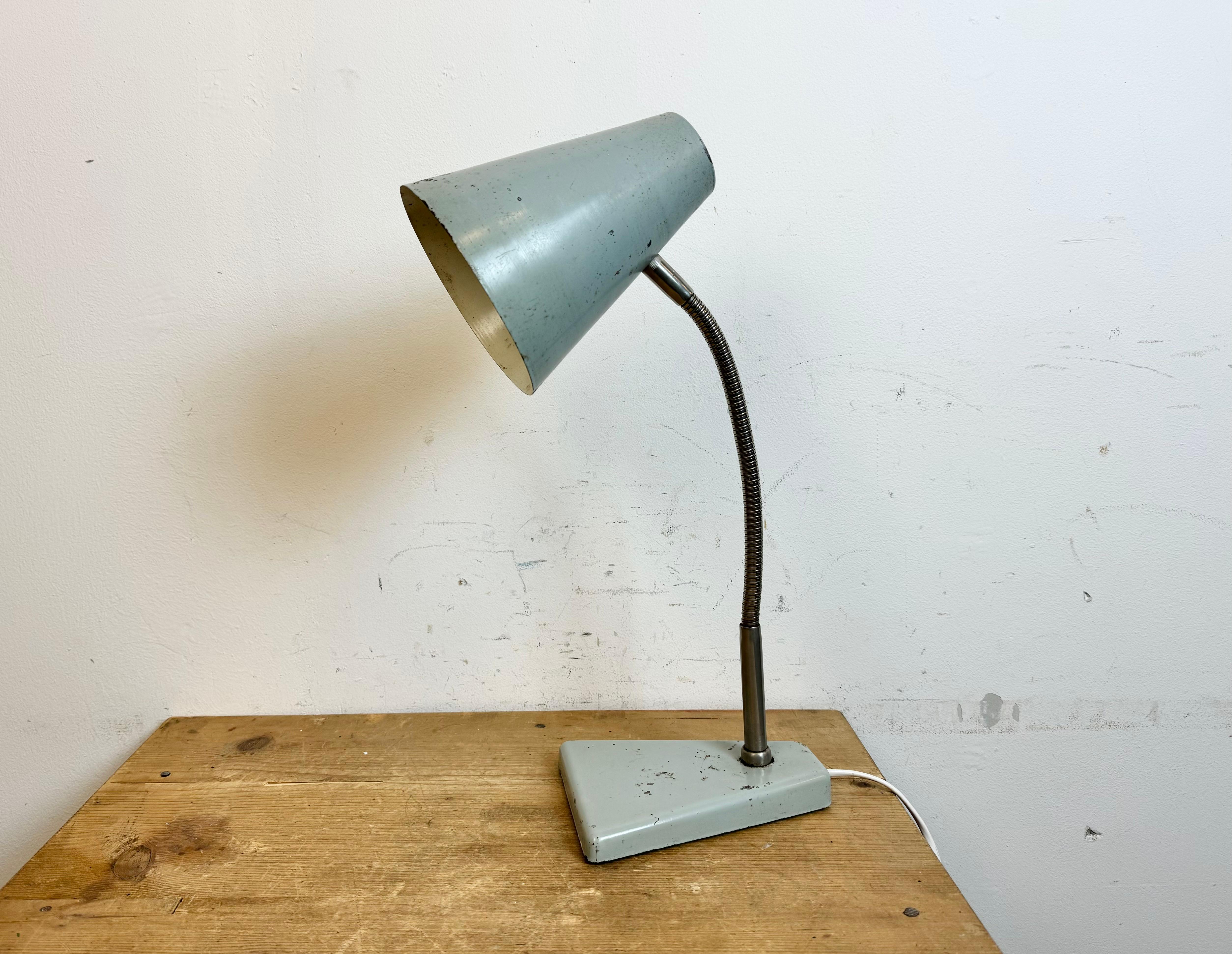 Industrial workshop table lamp made by Zaos in Poland during the 1960s.It features a grey metal base and shade and a  chrome plated gooseneck. The original socket requires E27/E26 lightbulbs.
The diameter of the shade is 15 cm. The weight of the