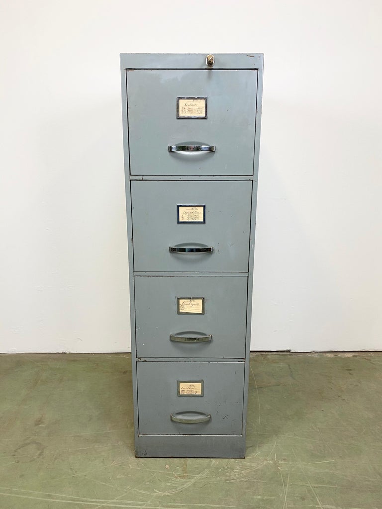 Grey metal filing cabinet designed and manufactured in former Czechoslovakia during the 1960s.
It features an iron body and a four metal drawers equipped with handles and label fields. The drawers can be locked. The weight of the cabinet is 90
