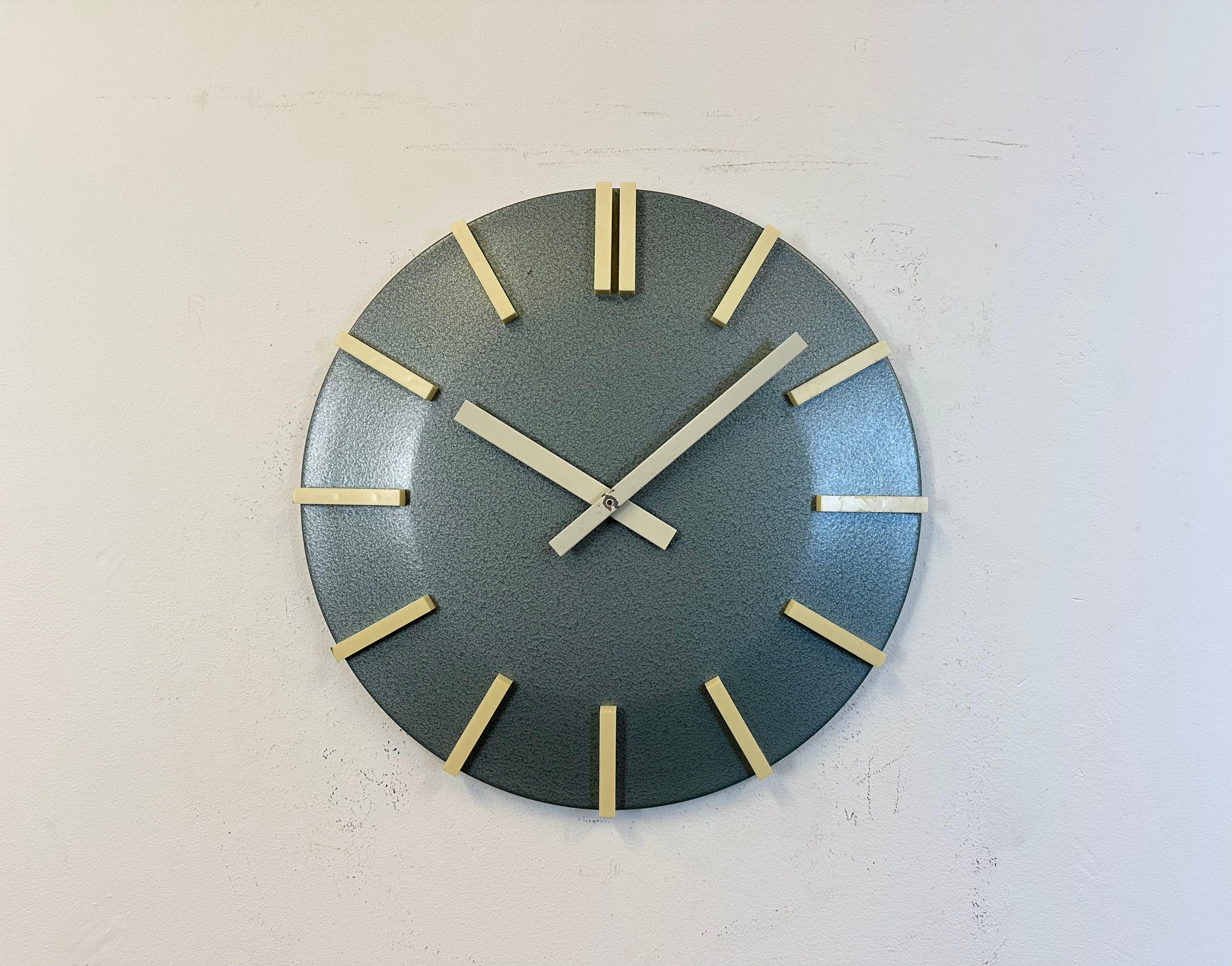 Industrial blue grey hammerpaint office wall clock was produced by Pragotron during the 1970s in former Czechoslovakia. Clock face with white plastic numerals is made from metal. Diameter is 40 cm. The piece has been converted into a battery-powered