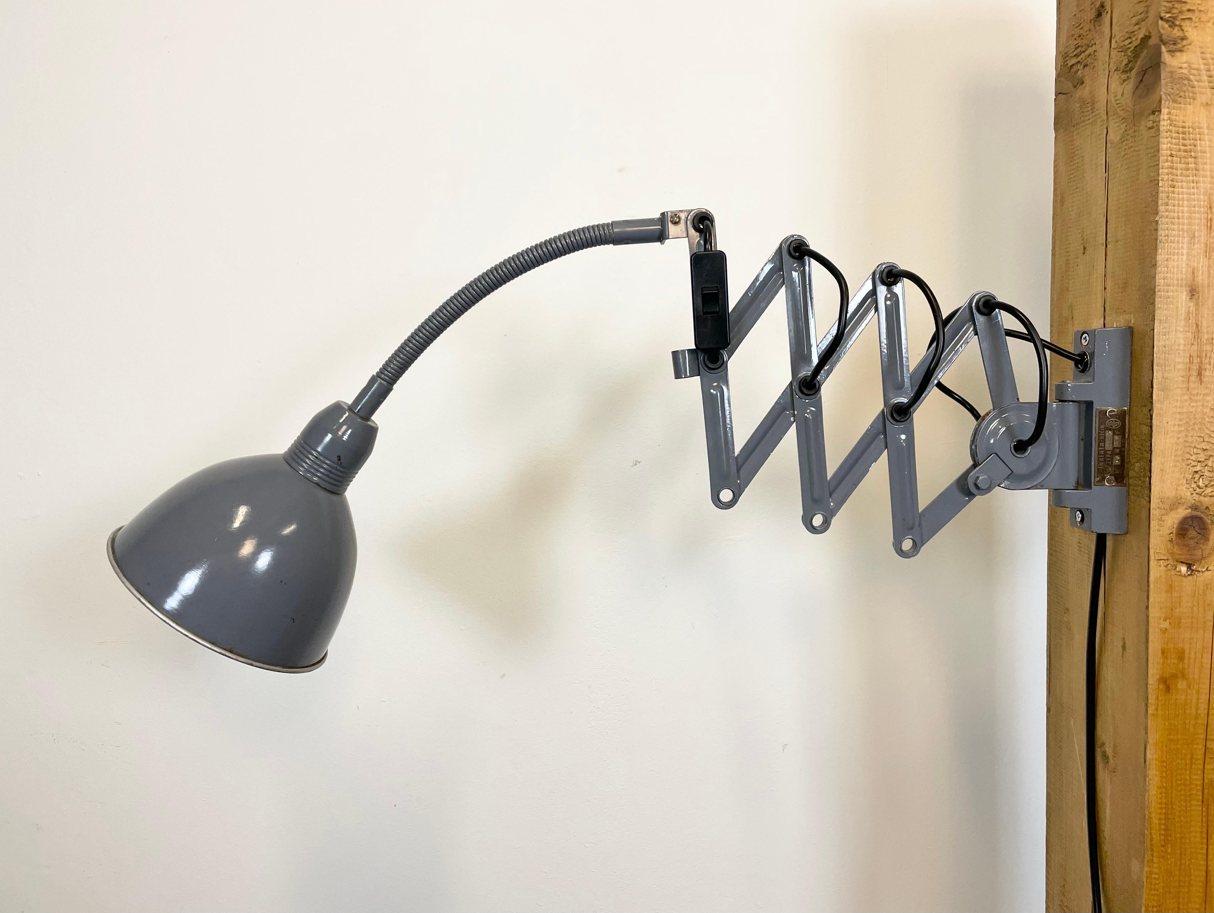 This grey vintage Industrial scissor wall light was produced by Elektroinstala in former Czechoslovakia during the 1960s. It has a metal lampshade. The iron scissor arm is extendable and can be turned sideways. The socket requires E 27 lightbulbs .