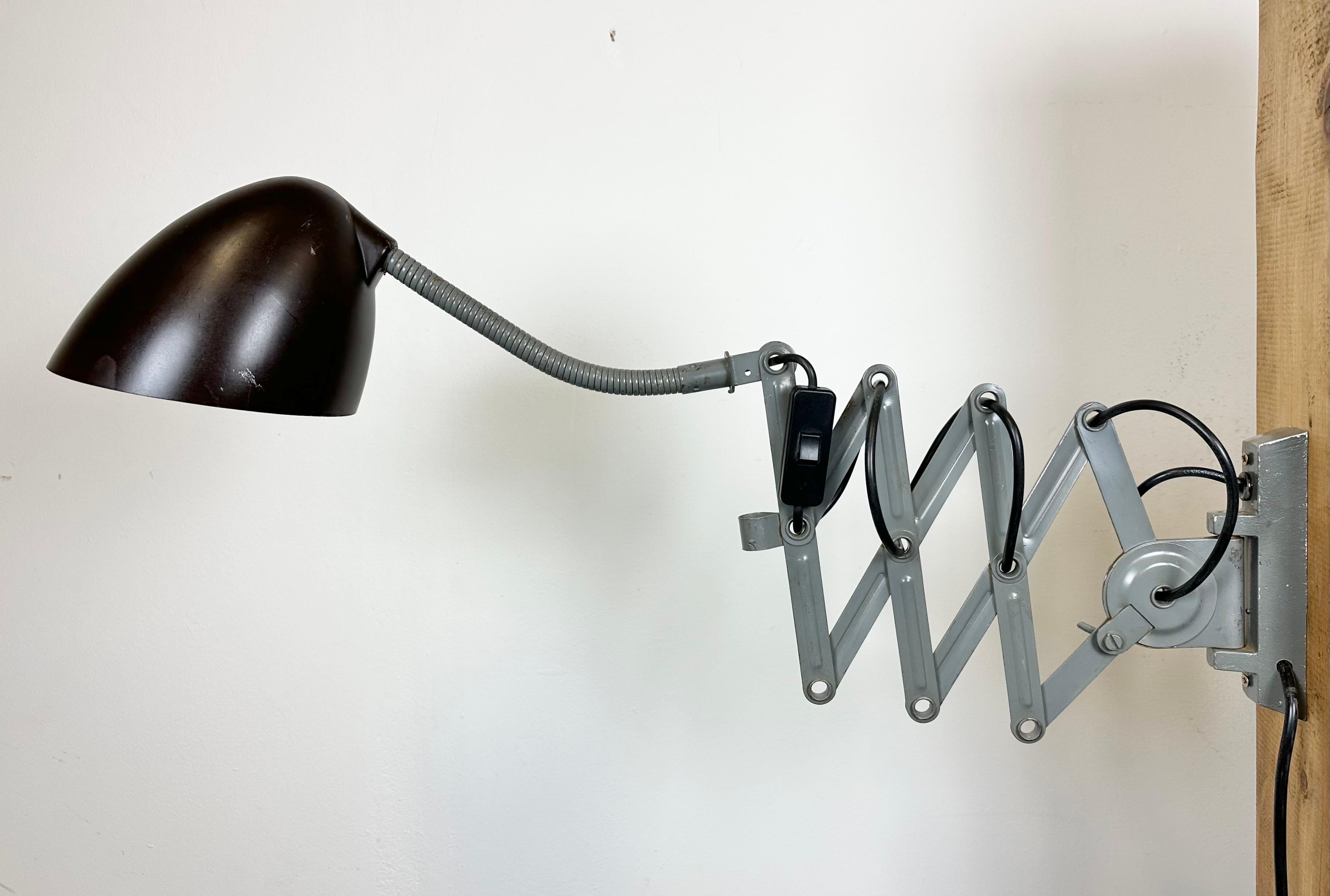 This vintage Industrial scissor wall light was produced by Elektroinstala in former Czechoslovakia during the 1960s. Lamp has a brown bakelite shade. Grey iron scissor arm is extendable and can be turned sideways. Fully functional. The original
