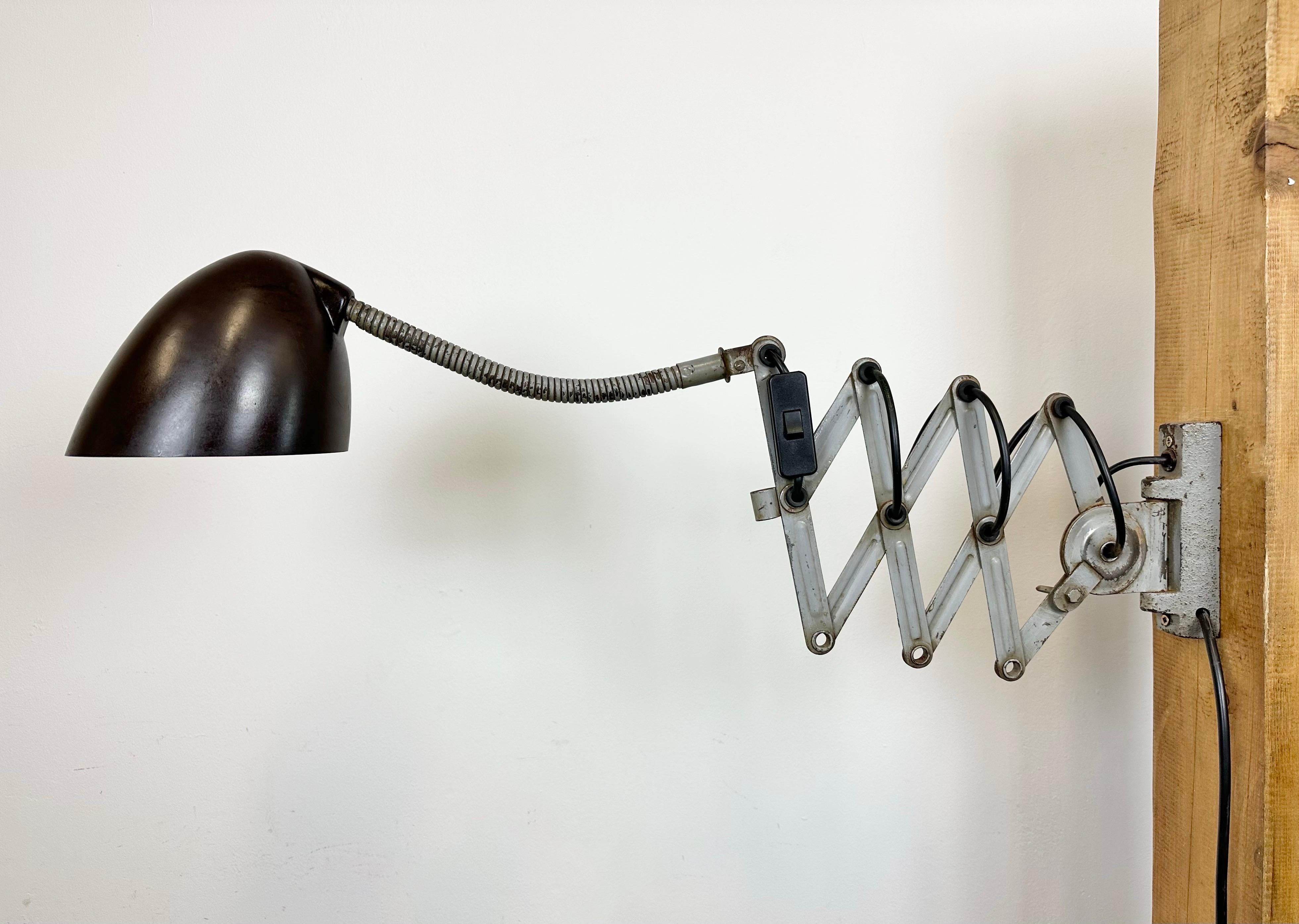 This vintage Industrial scissor wall light was produced by Elektroinstala in former Czechoslovakia during the 1960s. Lamp has a brown bakelite shade. Grey iron scissor arm is extendable and can be turned sideways. Fully functional. The original